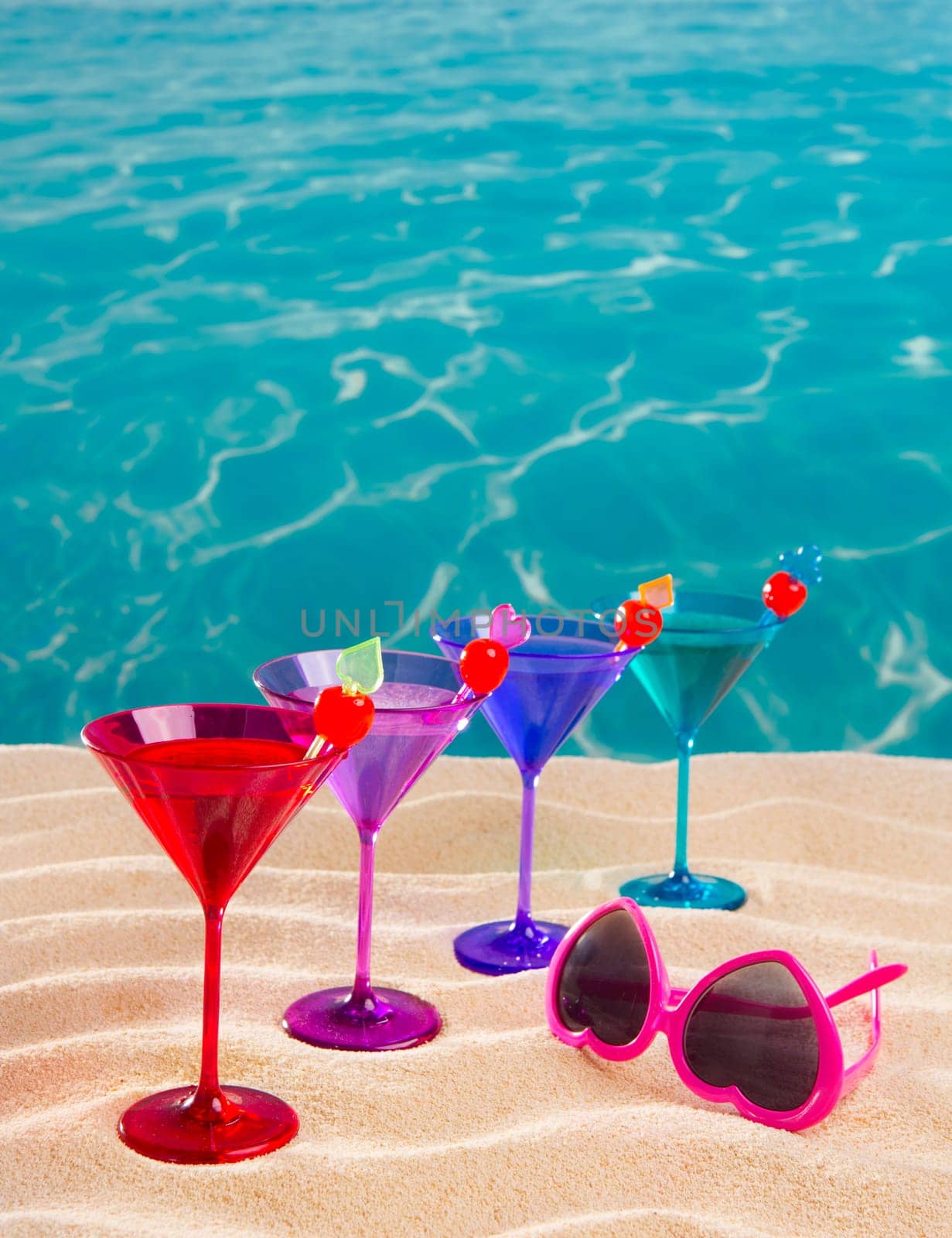 colorful cocktail in a row with cherry on tropical sand beach of turquoise sea