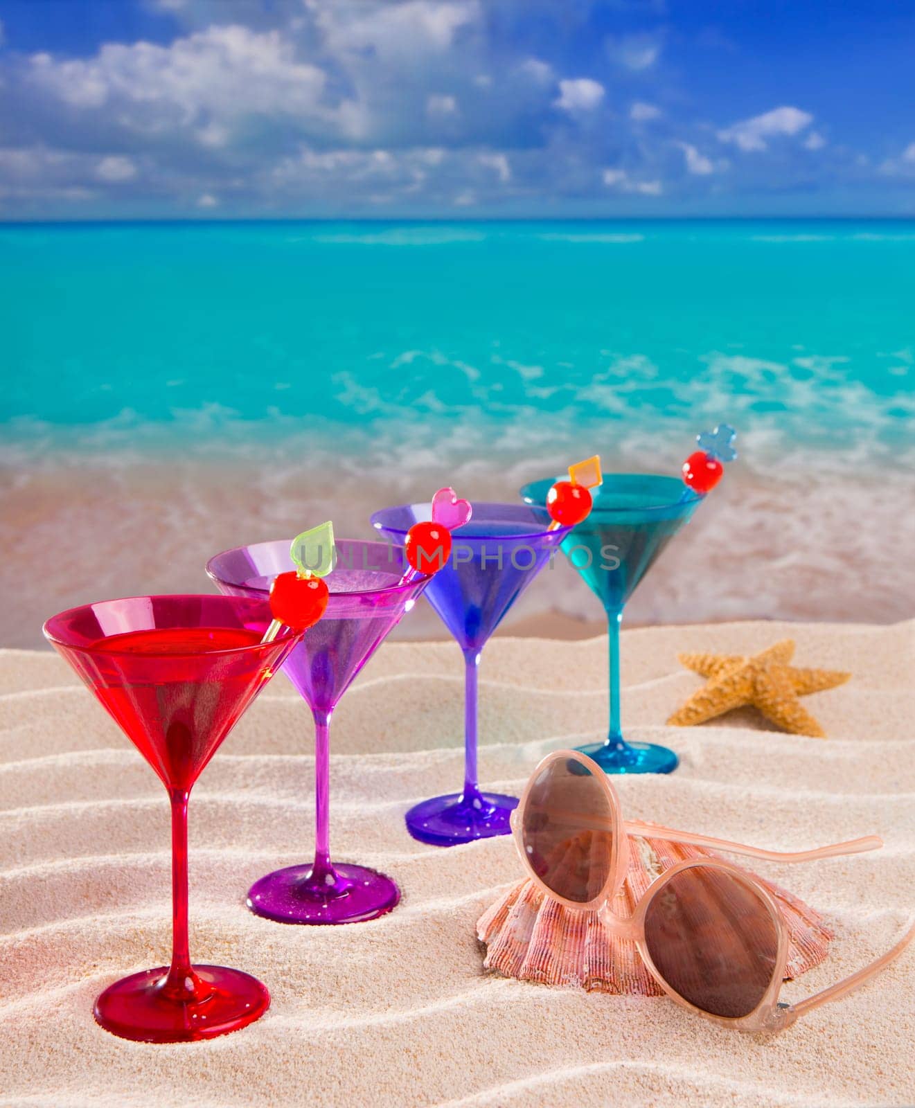 colorful cocktail in a row with cherry on tropical sand beach of turquoise sea