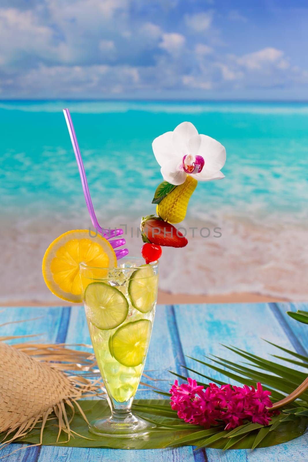 Lemon lime cocktail mojito on tropical turquoise beach on blue wood