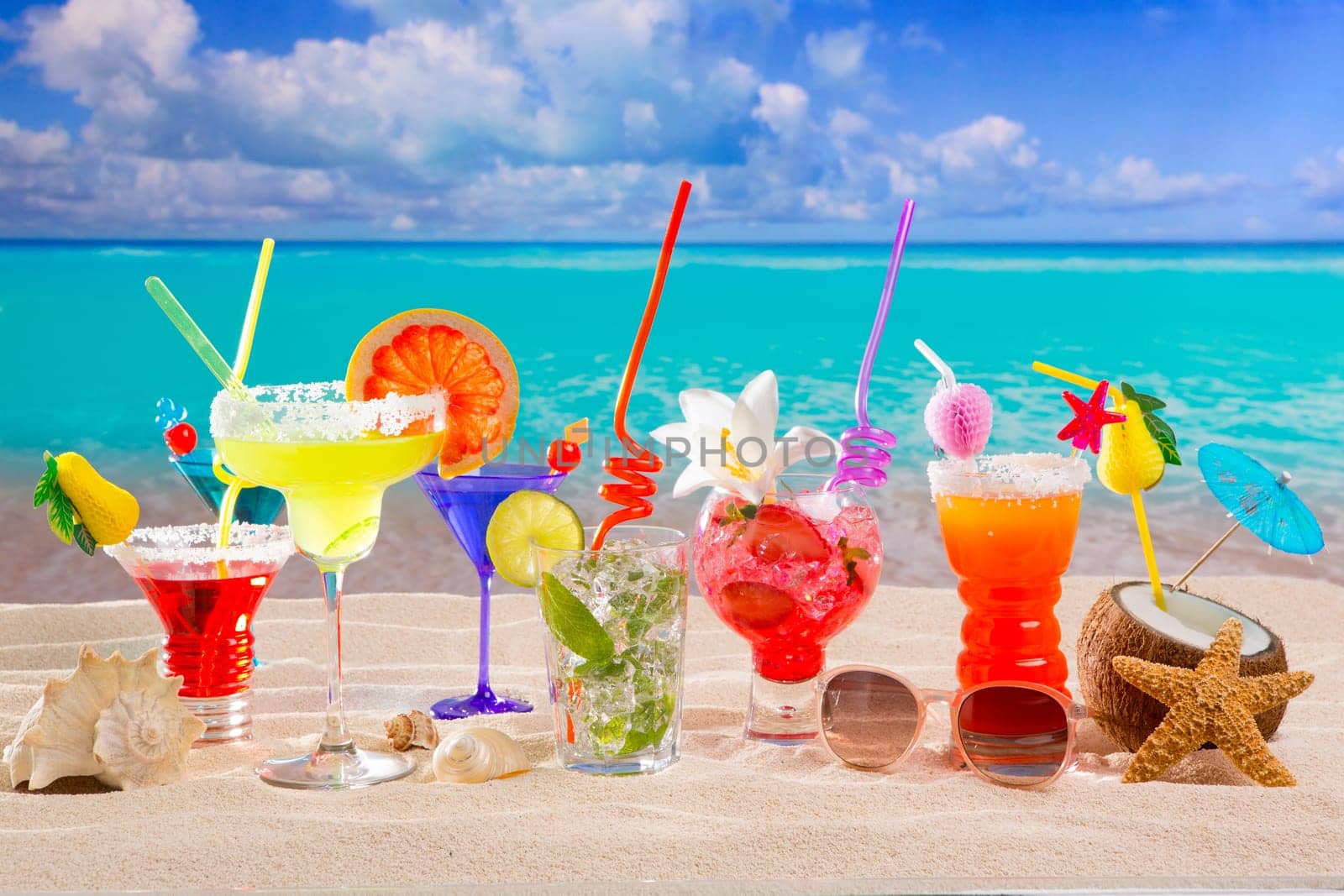 Colorful tropical cocktails at beach on white sand and turquoise water
