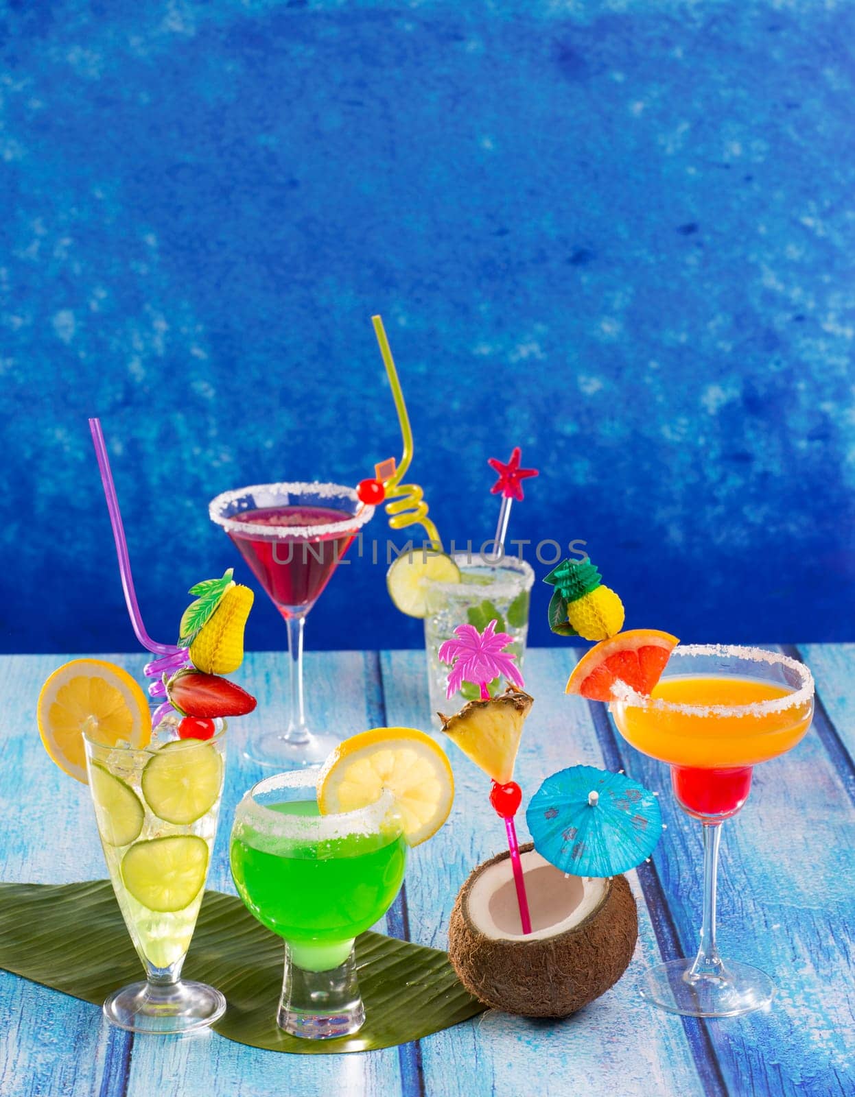 Colorful varied tropical Cocktails in tropical blue wood with coconut mojito pepermint margarita