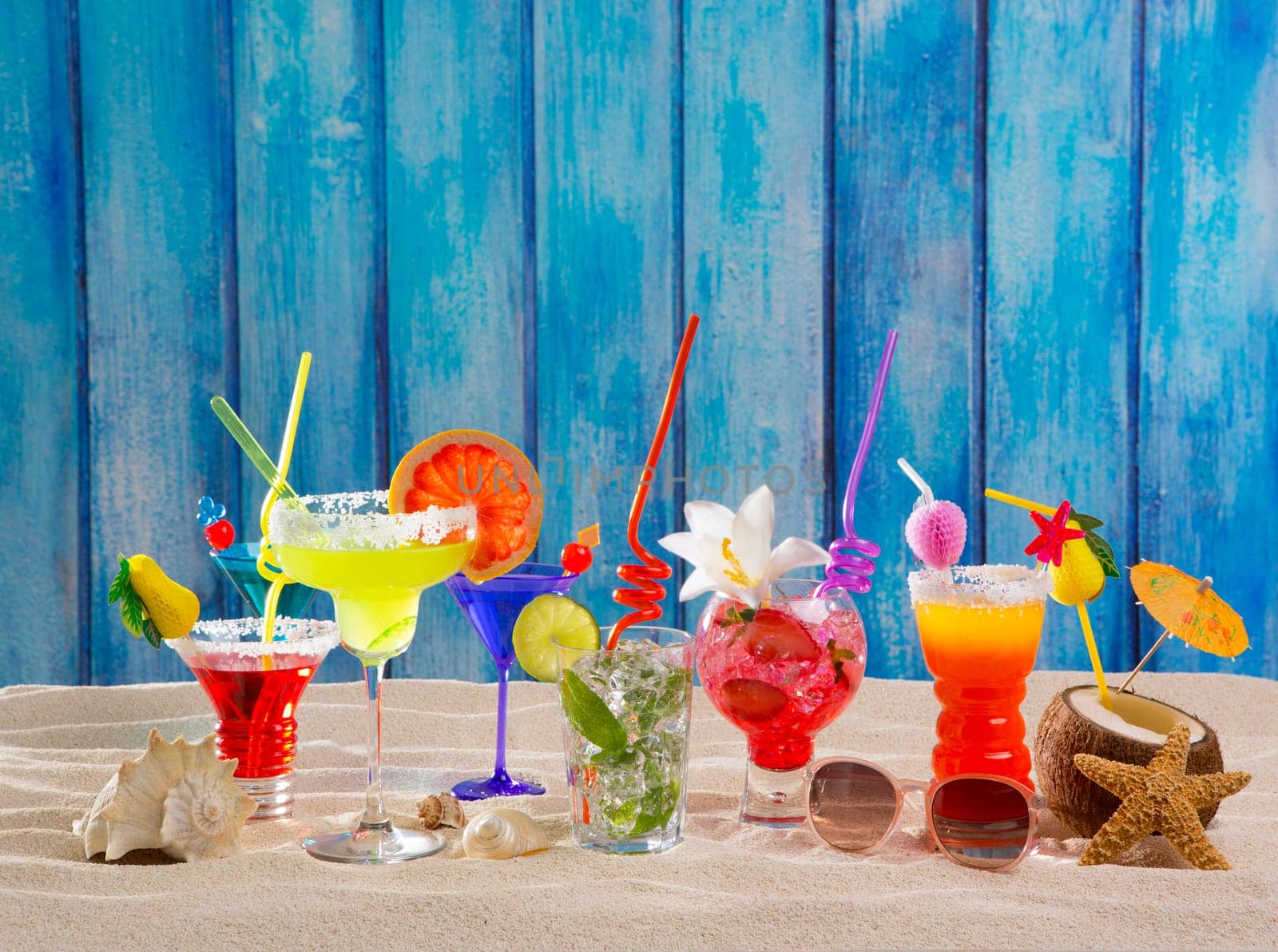 Colorful tropical cocktails at beach on blue grunge wood wall