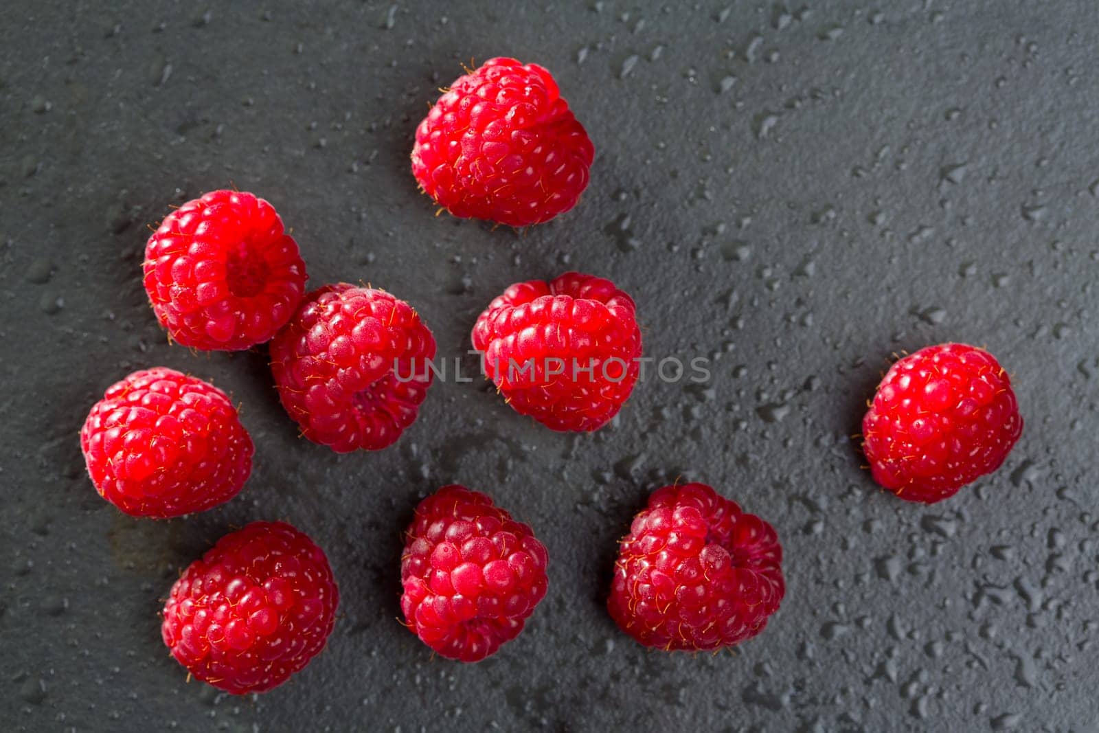 berries raspberry on black background macro closeup with fresh water drops