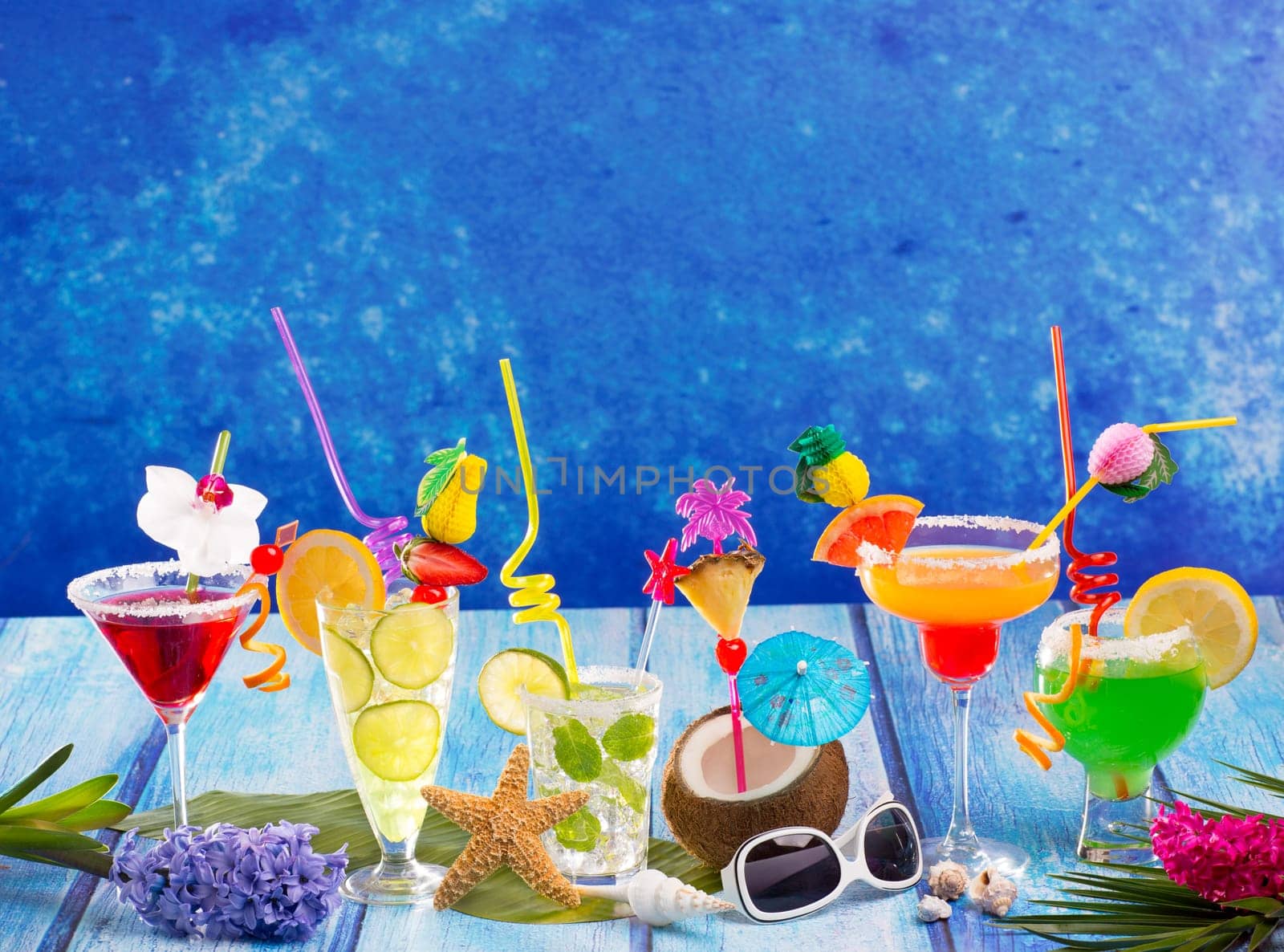 Colorful varied tropical Cocktails in tropical blue wood with coconut mojito pepermint margarita