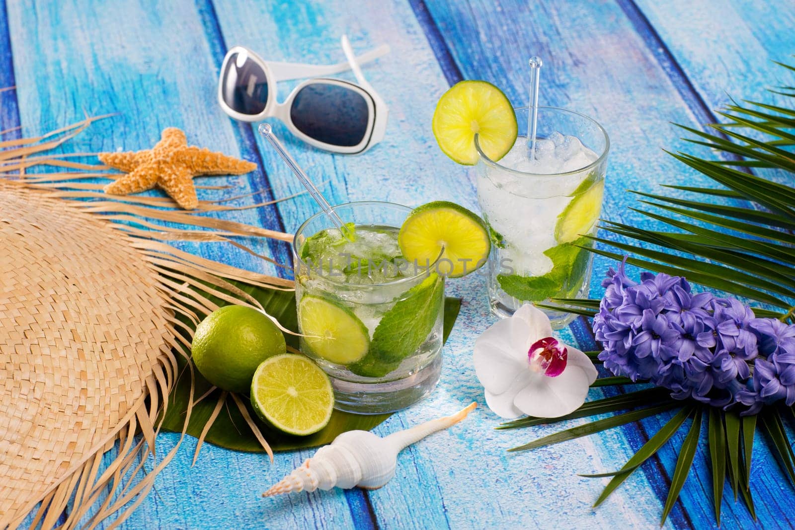 Cuban Mojito cocktail in tropical blue wood with sunglasses flowers and starfish
