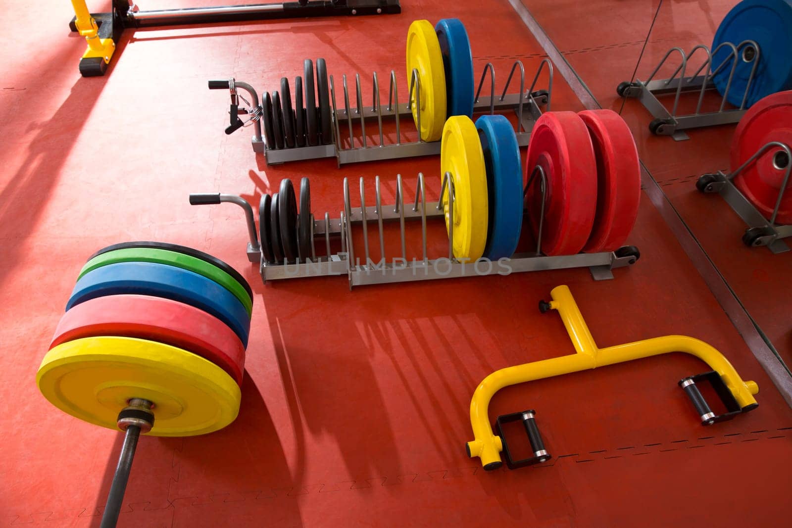 Crossfit fitness gym weight lifting bar colorful equipment on red floor