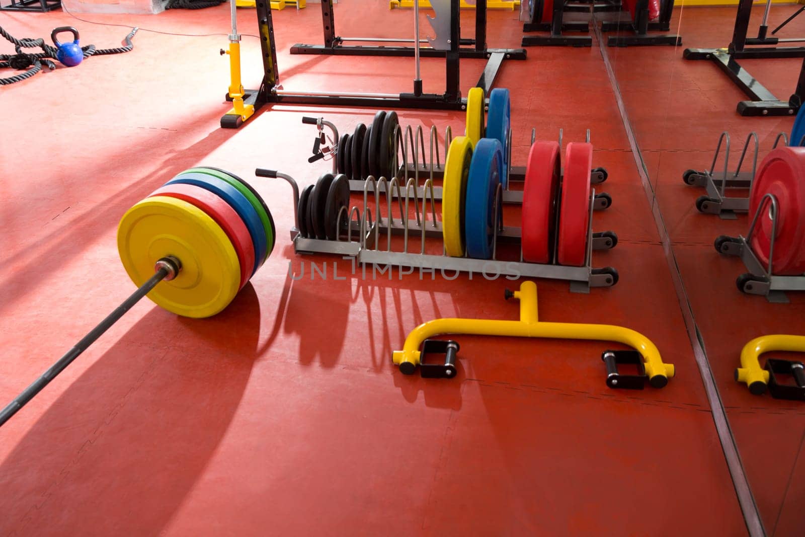 Crossfit fitness gym weight lifting bar colorful equipment on red floor