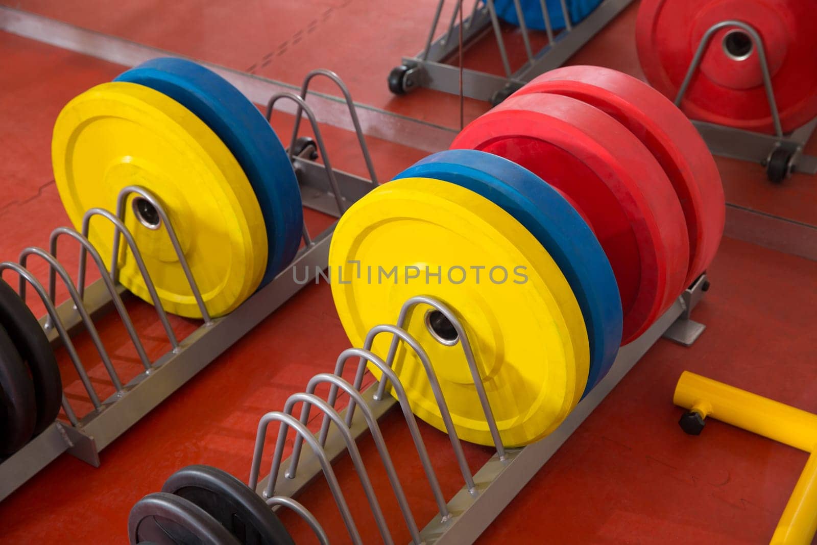Crossfit fitness gym weight lifting bar colorful equipment on red floor