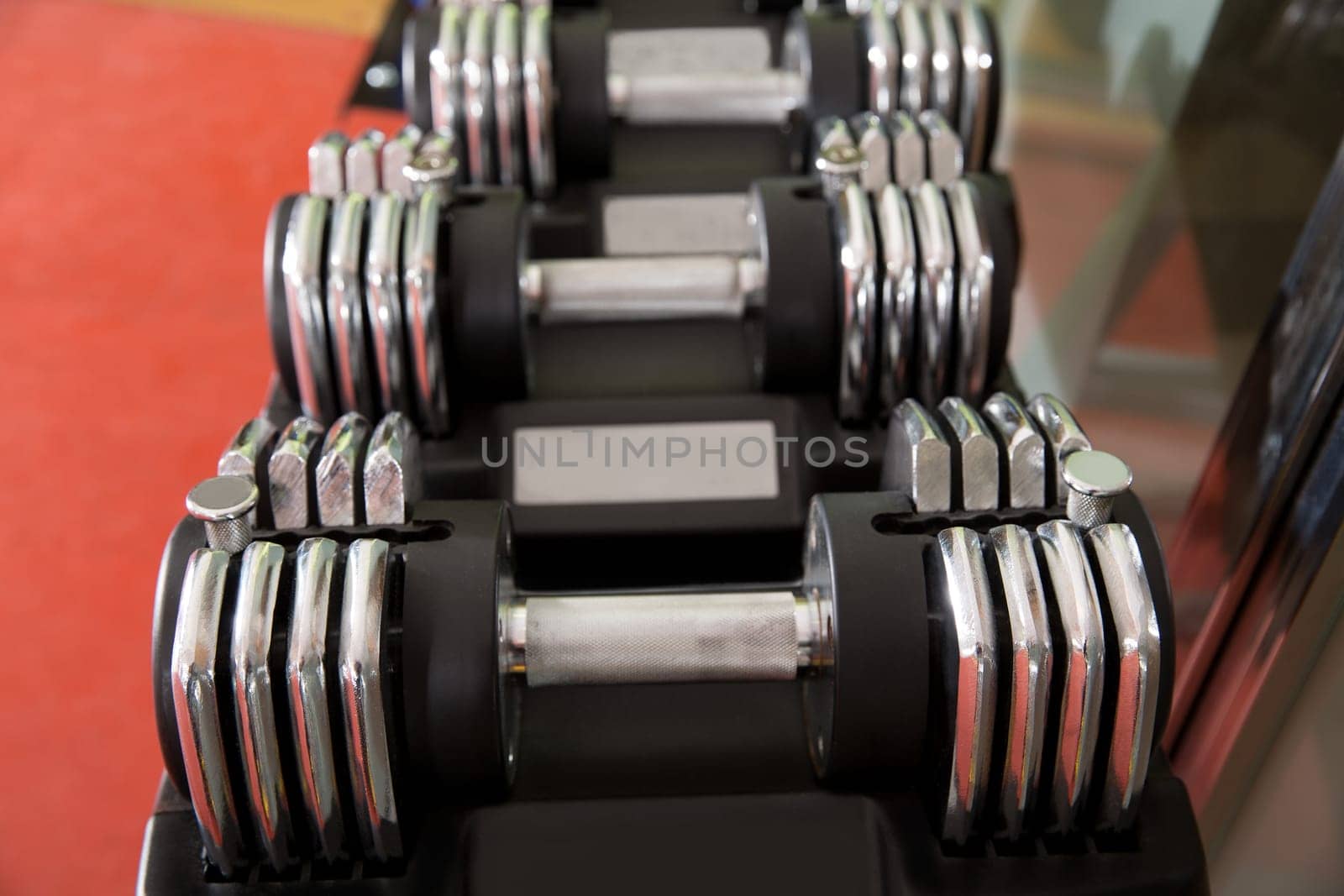 Adjustable weight dumbbells in a row with selective focus in foreground