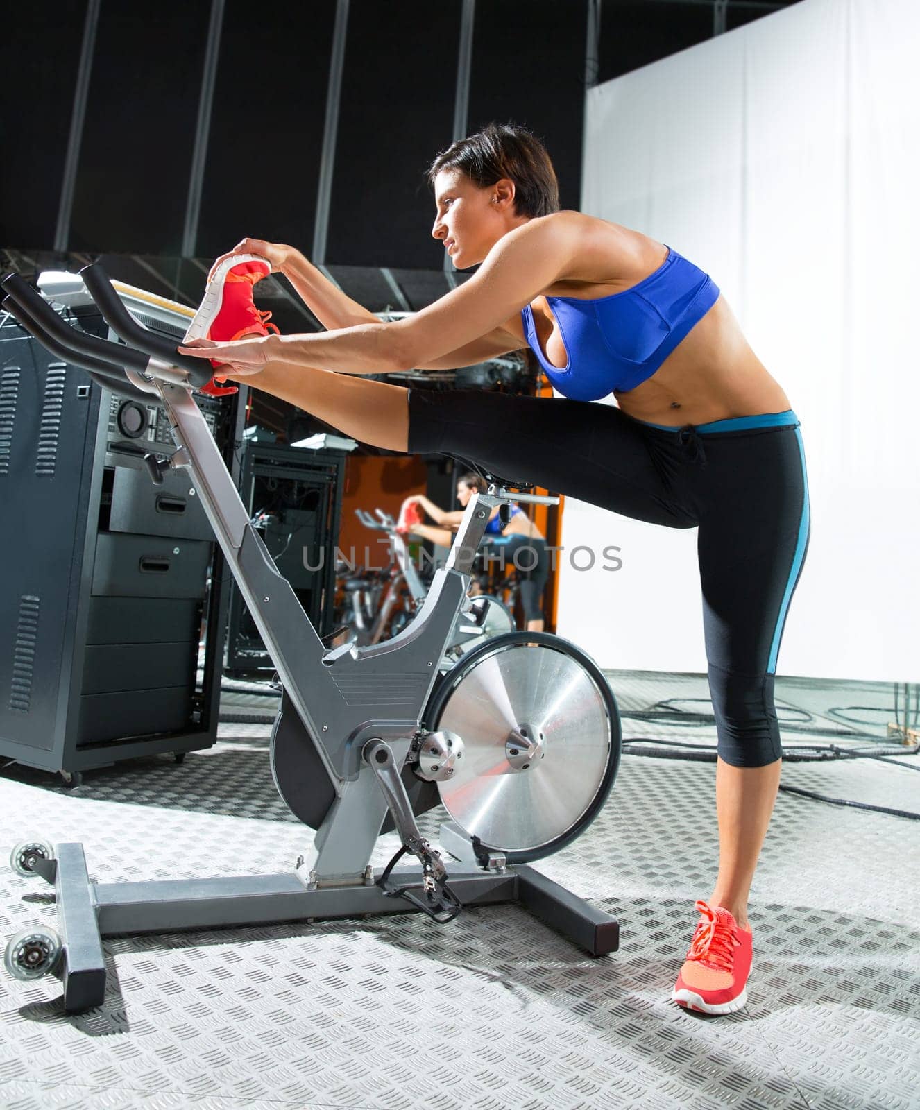 Aerobics spinning monitor trainer woman stretching exercises after workout at gym