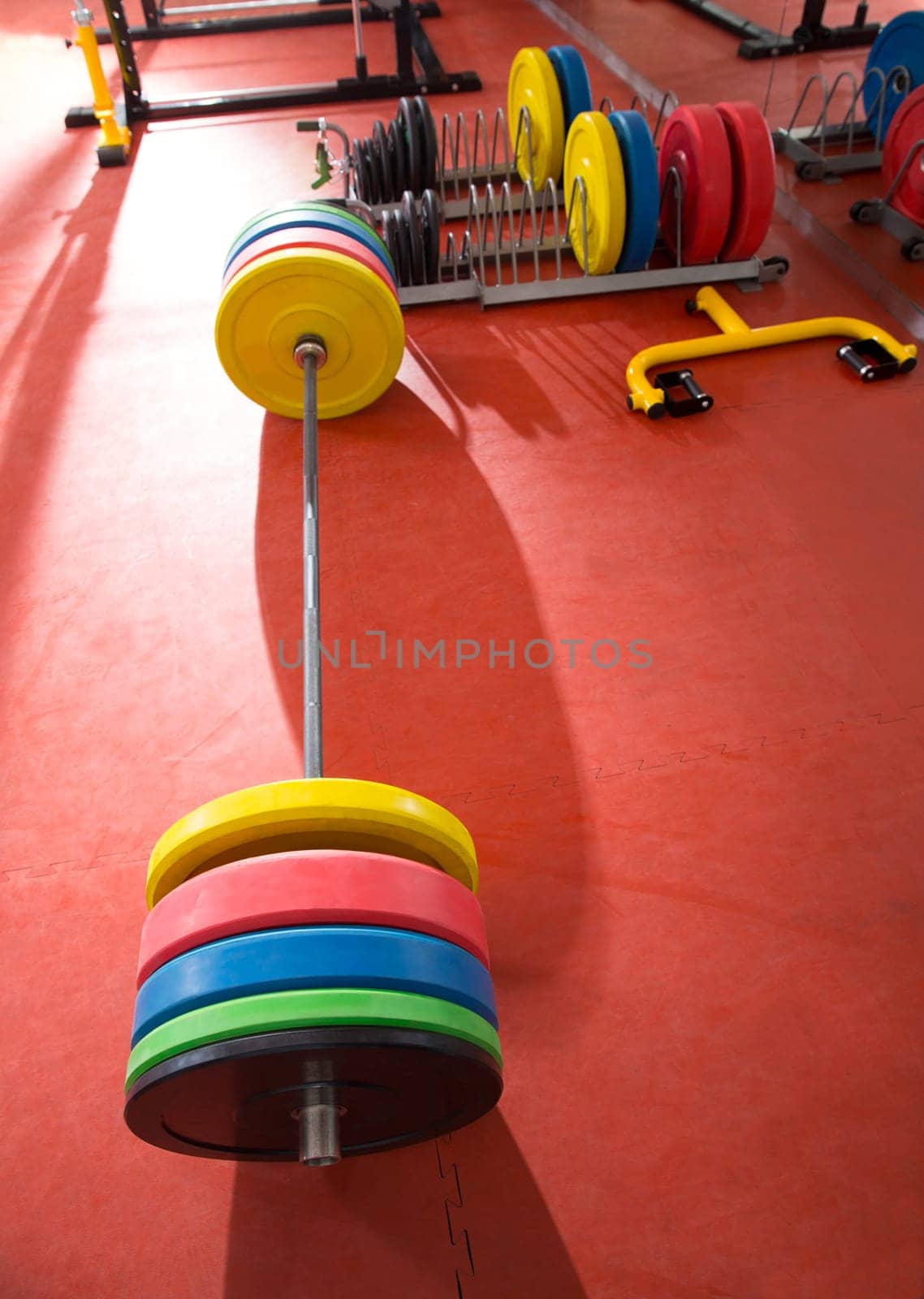 Crossfit fitness gym weight lifting bar colorful equipment on red floor