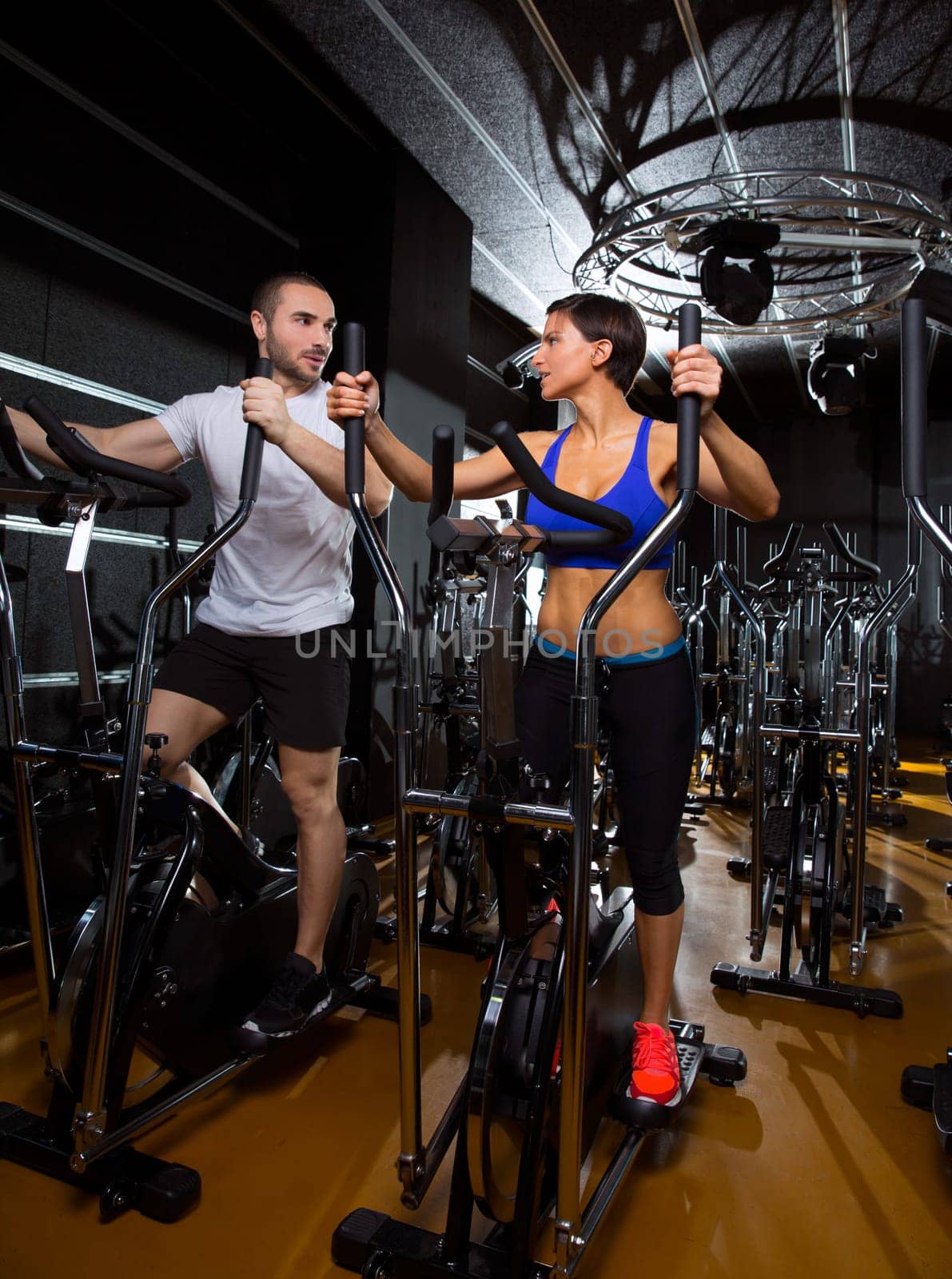 elliptical walker trainer man and woman at black gym training aerobics exercise