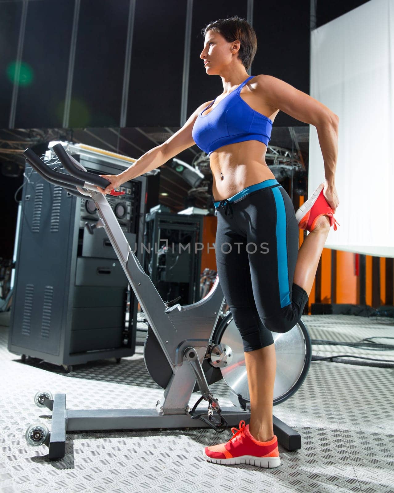 Aerobics spinning monitor trainer woman stretching exercises after workout at gym