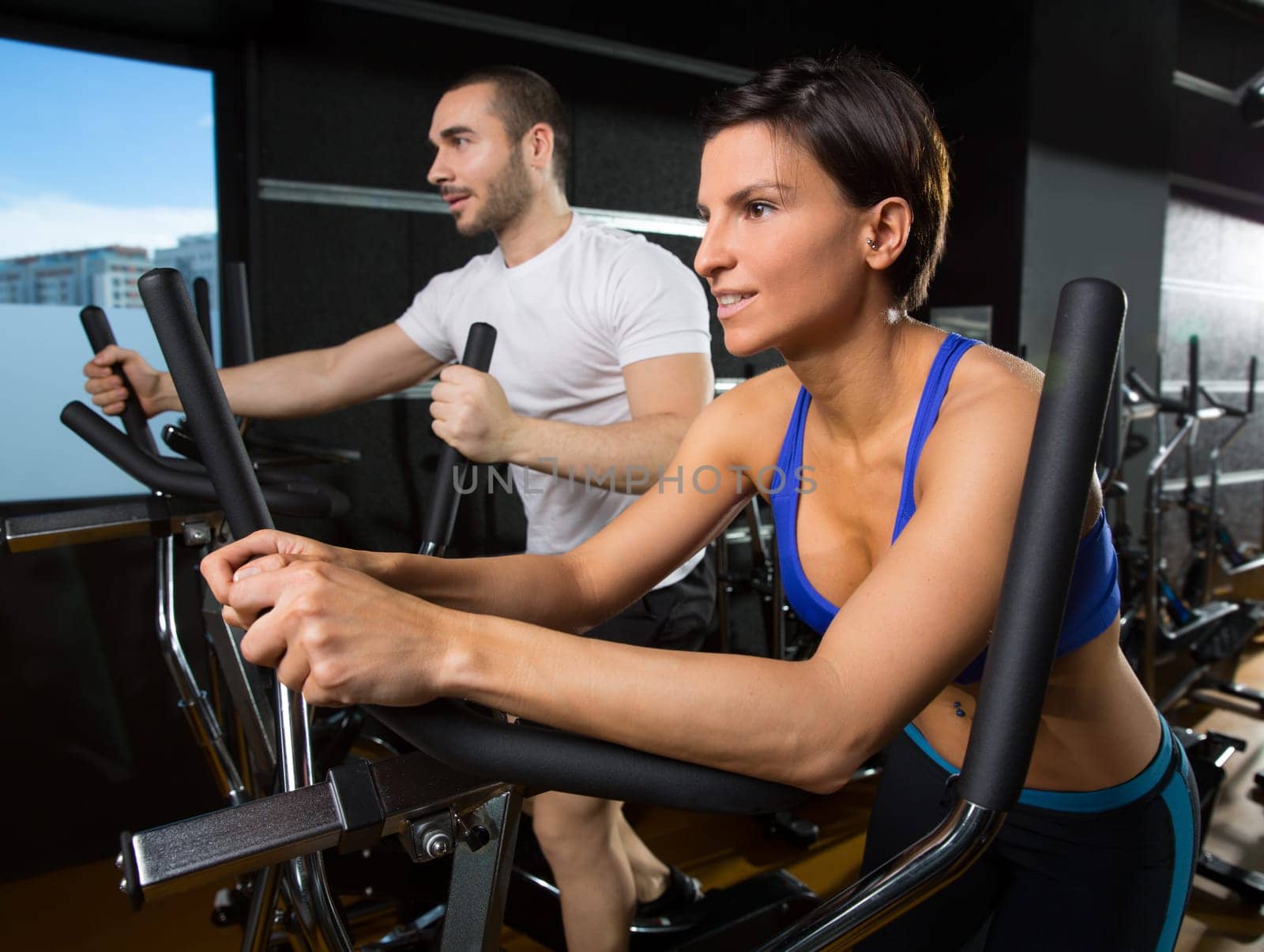 elliptical walker trainer man and woman at black gym training aerobics exercise