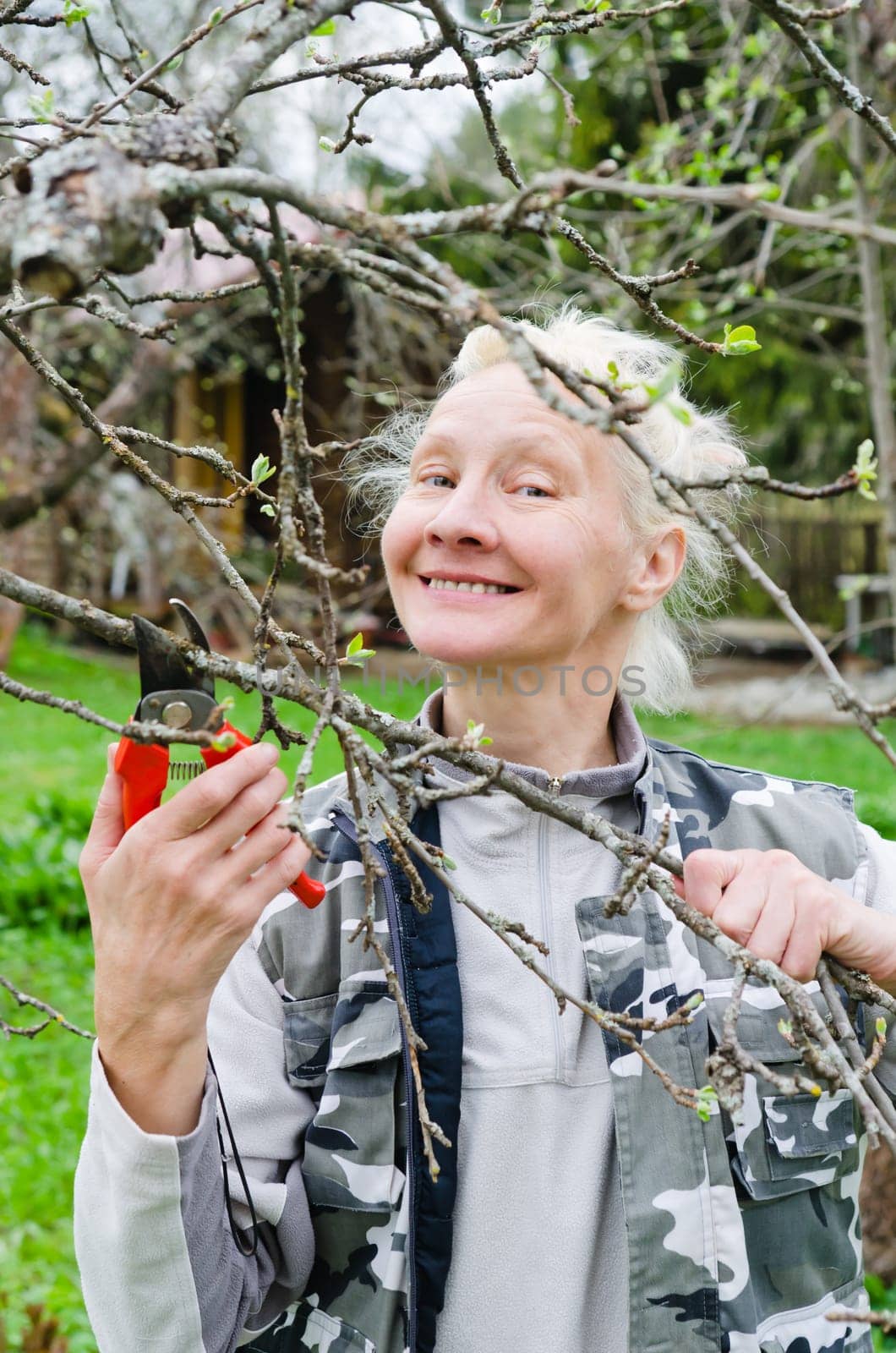 Woman cuts a branch at an Apple-tree, a spring in the garden