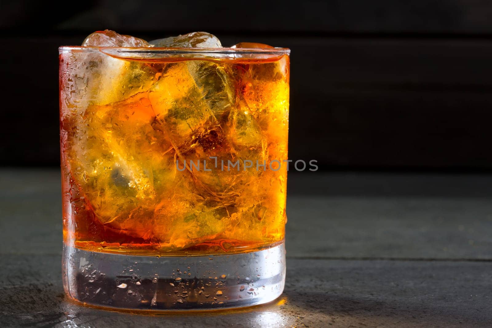 Whiskey whisky on the rocks on glass over gray black background