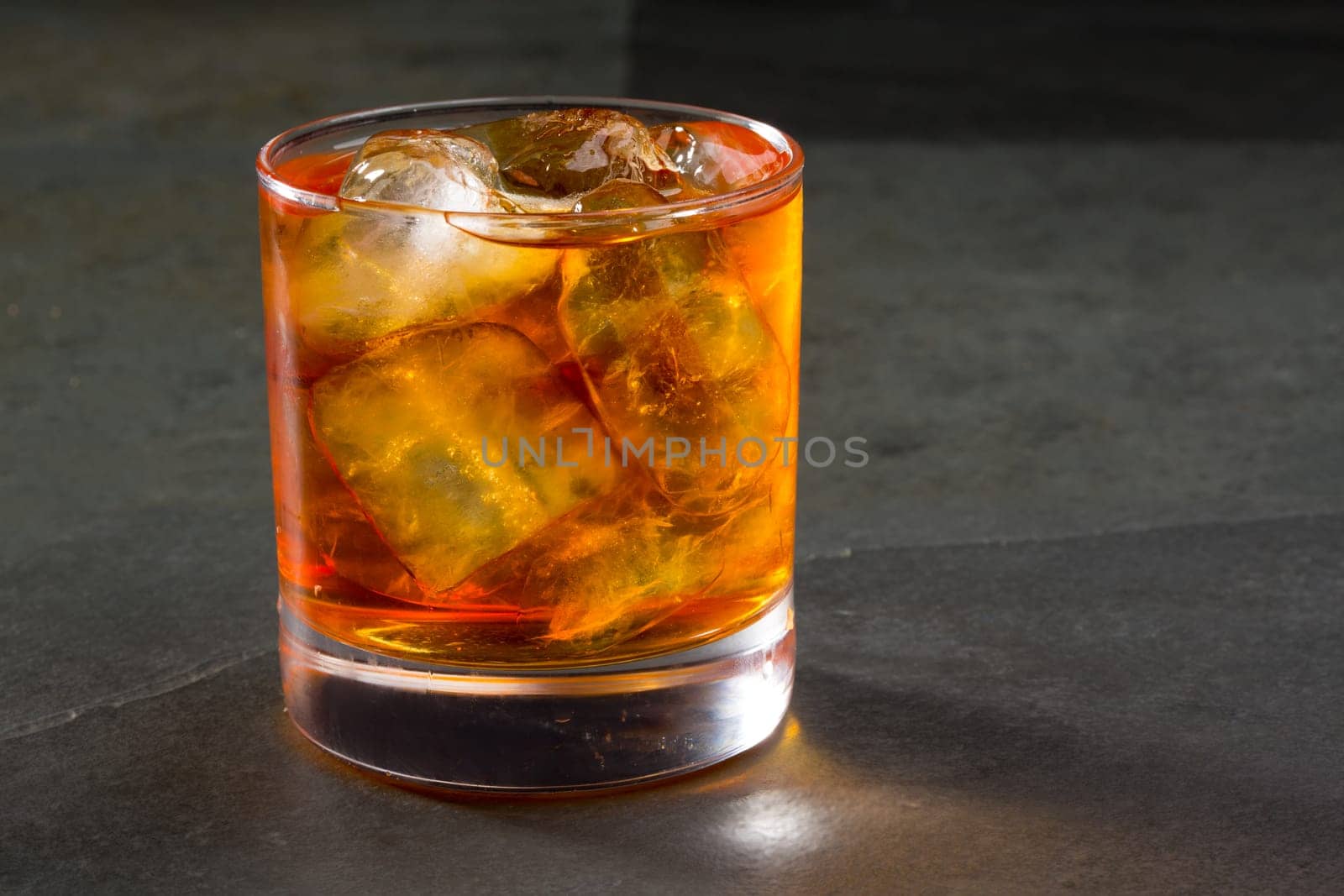 Whiskey whisky on the rocks on glass over gray black background