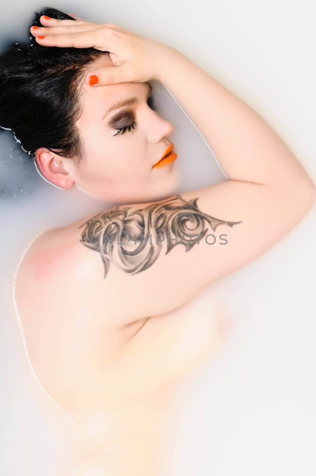 Adult woman lying in the bath with delight, showing her backsite