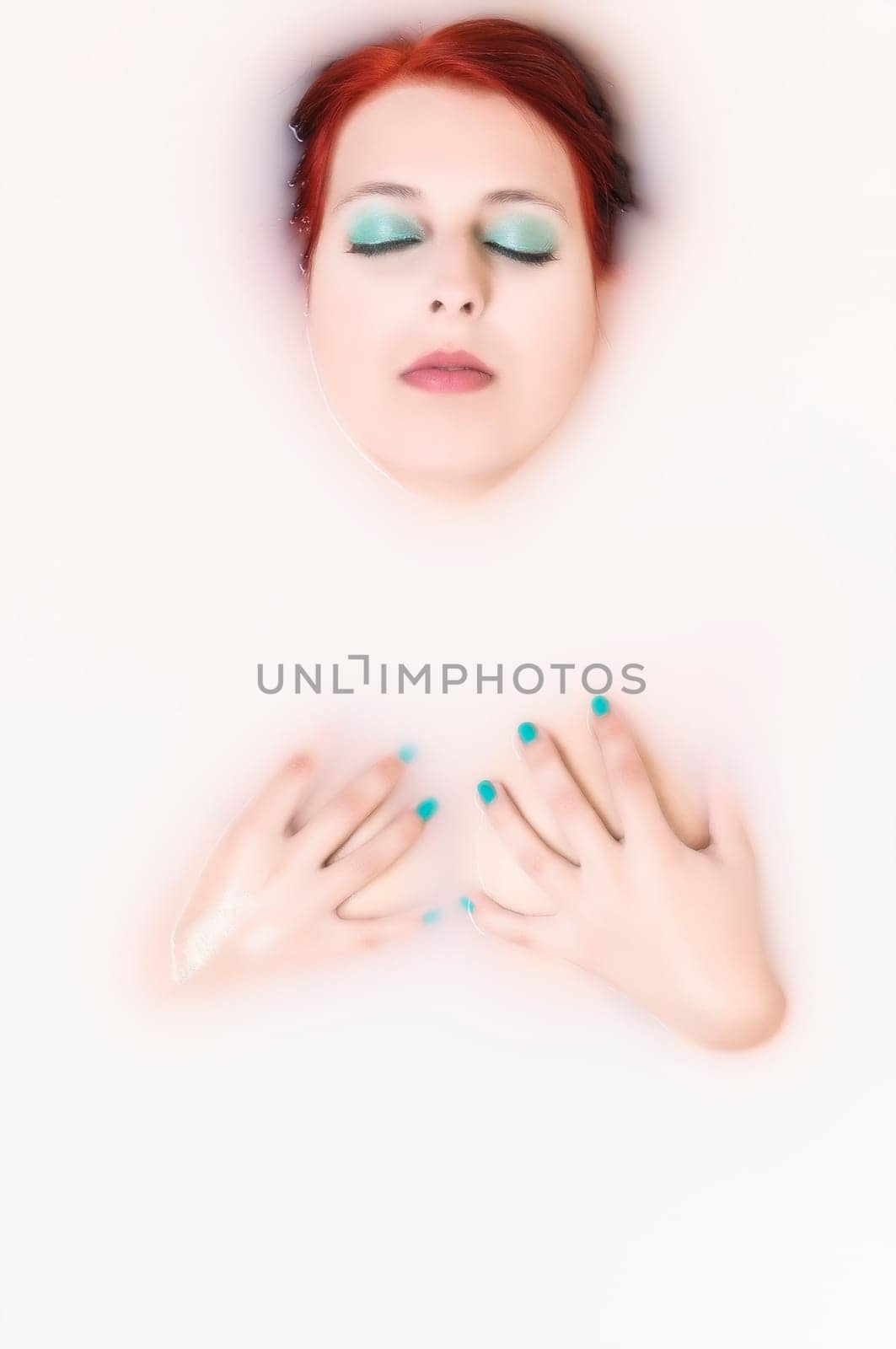 Beauty woman in bathroom with water with milk covering her breasts with her hands.