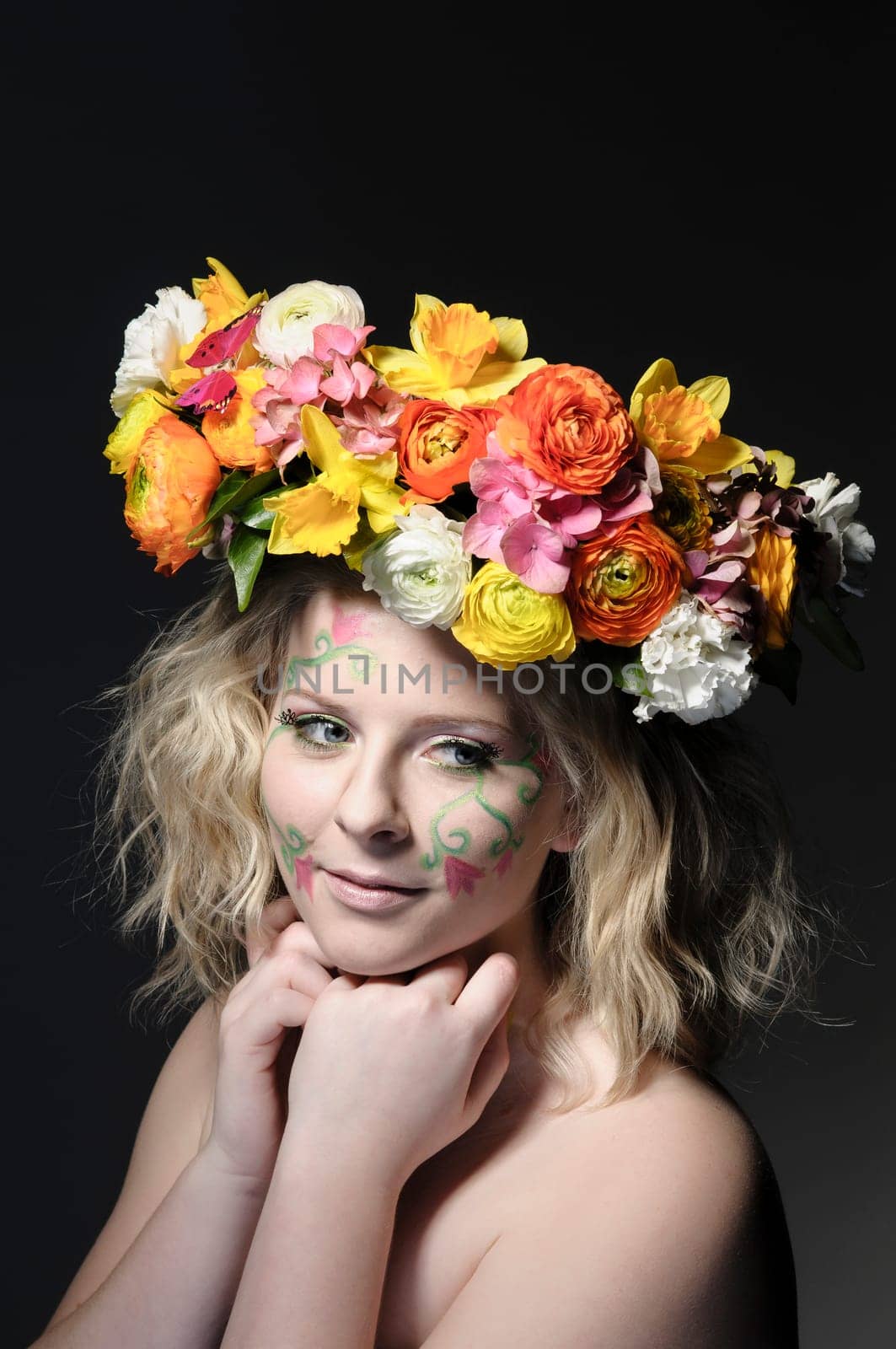 Spring portrait of a young woman with spring-like make-up and a colorful flower wreath in her hair.