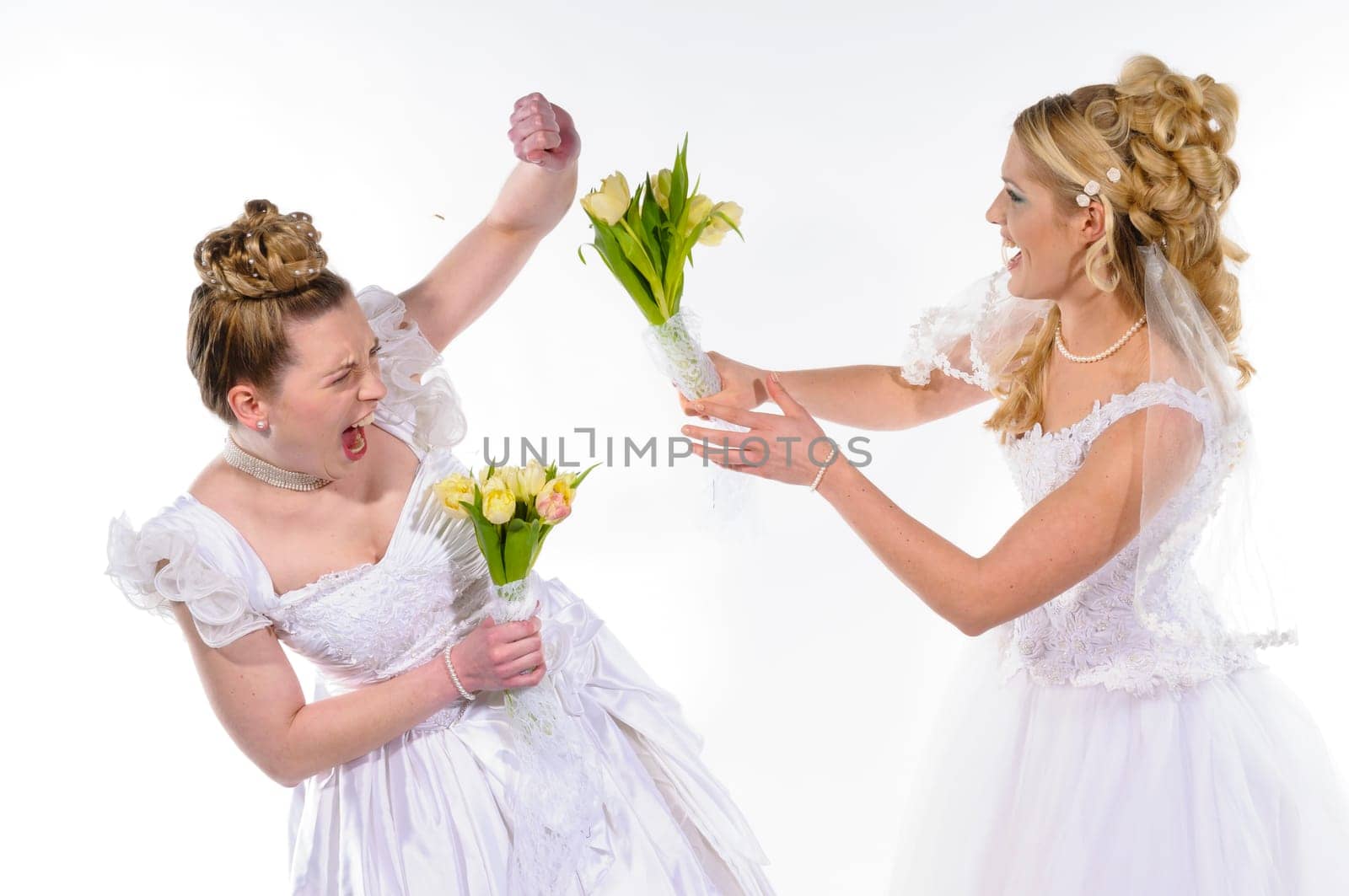 Two young brides in white wedding dresses fight against each other and beat with flowers