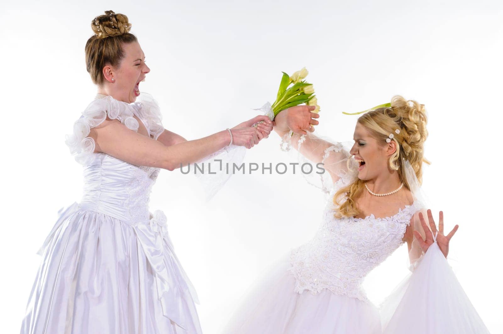 Two young brides in white wedding dresses fight against each other and beat with flowers