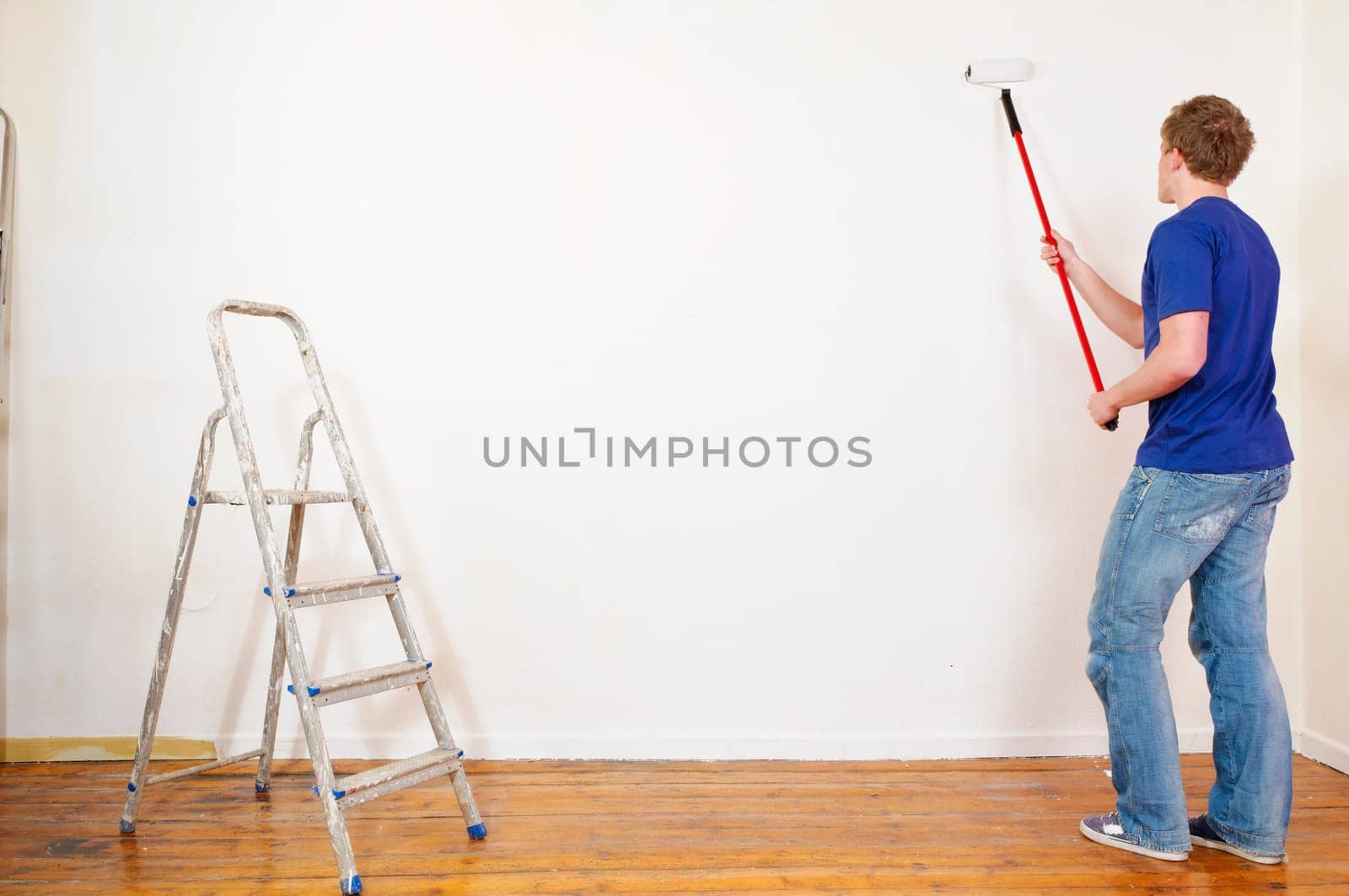 Young man in a T-shirt paints the walls of his first apartment in bright colors.