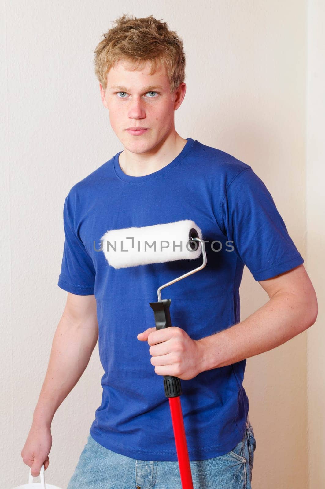Young man in a T-shirt paints the walls of his first apartment in bright colors.