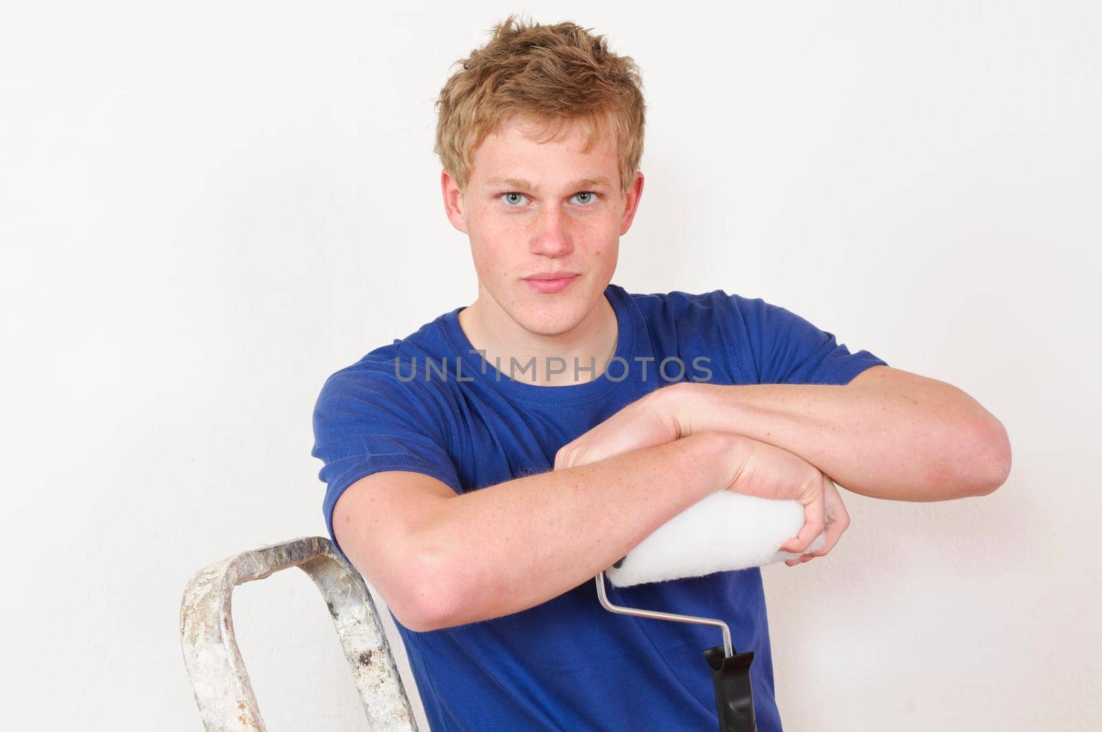Young man in a T-shirt paints the walls of his first apartment in bright colors.