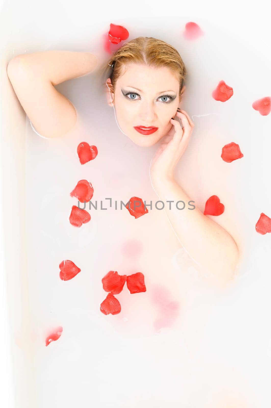 Portrait of a young woman taking a relaxing bath with rose petals