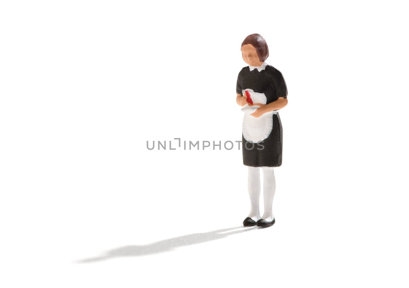 Miniature figure of a maid or hired help in a black uniform with white apron over a white background with copy space