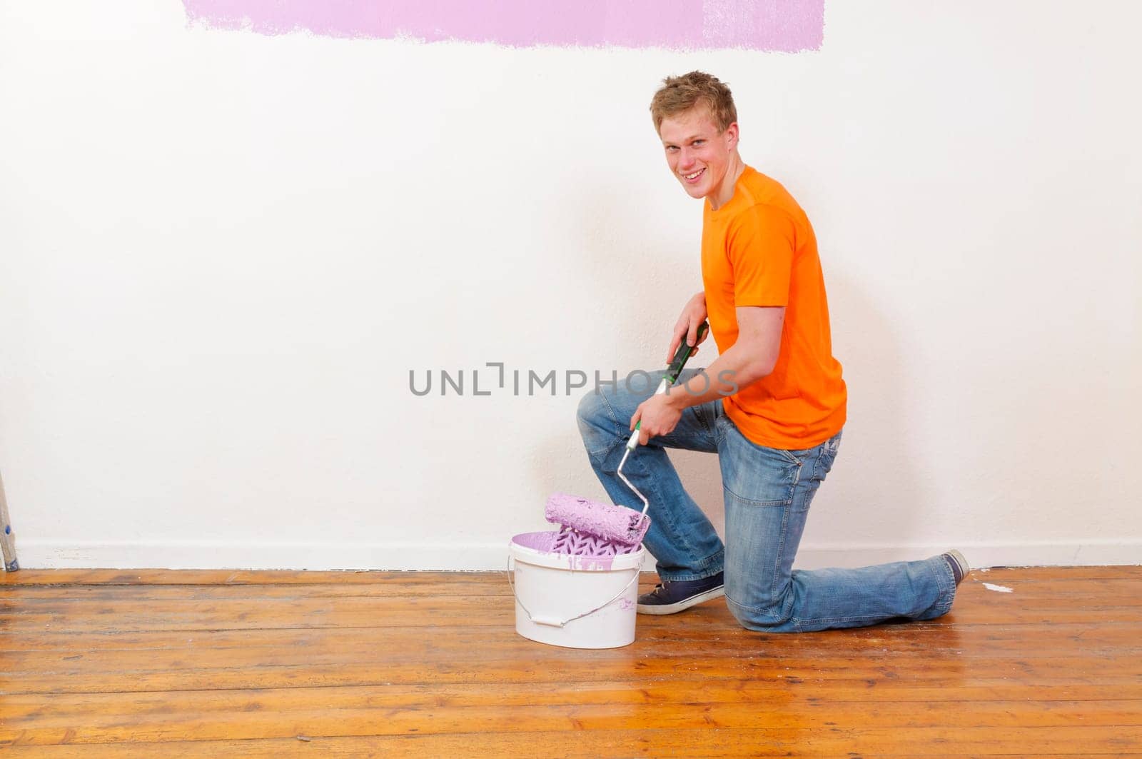 Young man in a T-shirt paints the walls of his first apartment in bright colors.