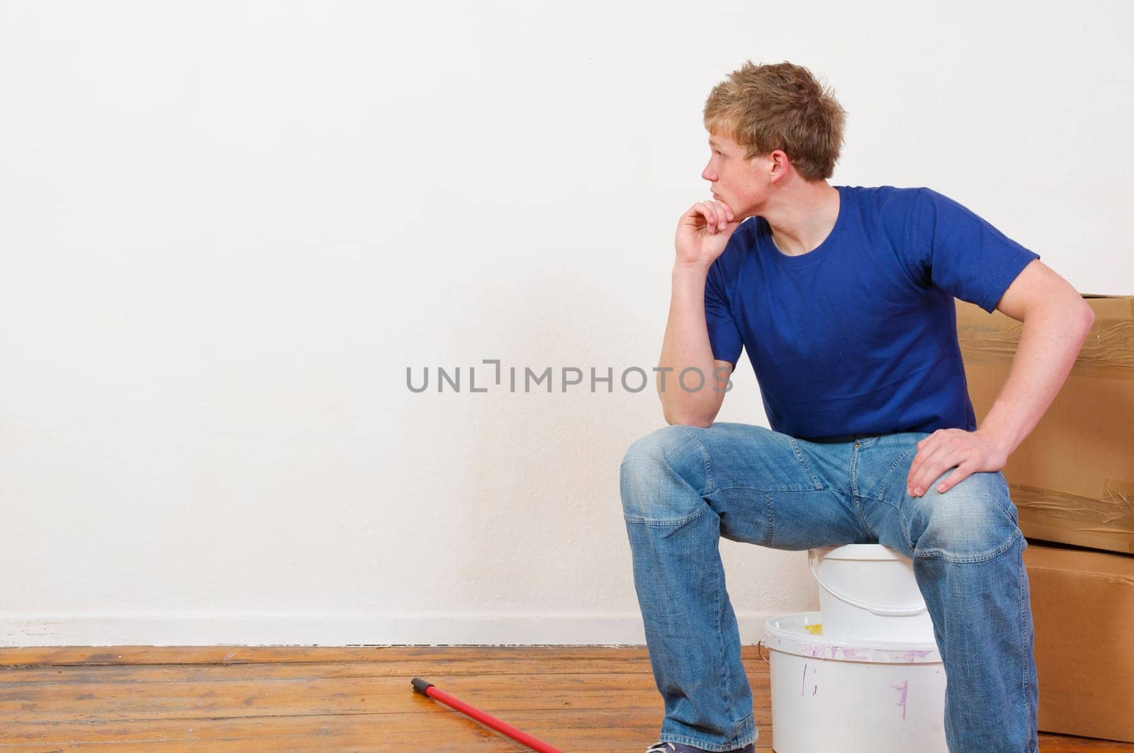 Young man in a T-shirt paints the walls of his first apartment in bright colors.
