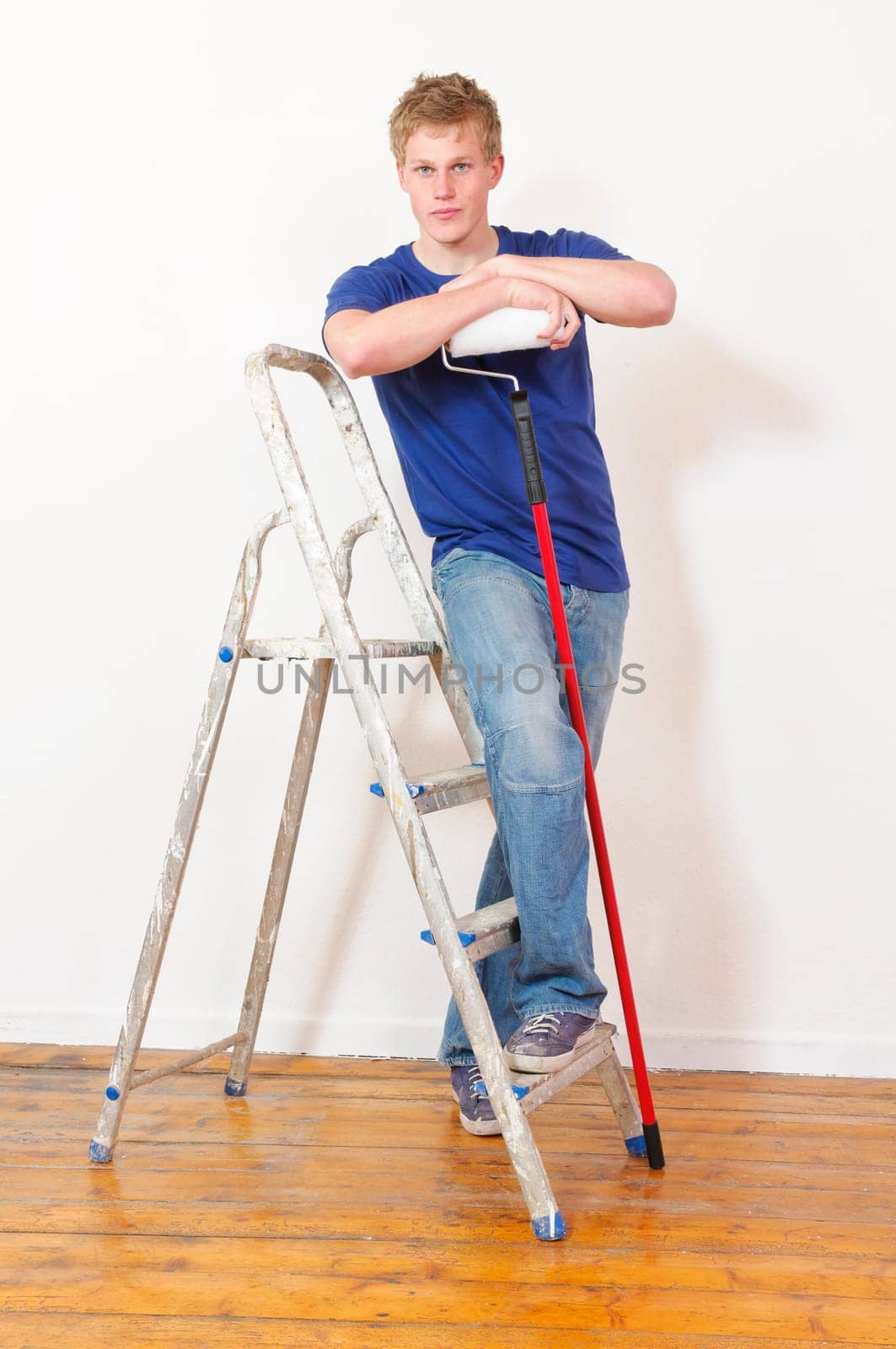 Young man in a T-shirt paints the walls of his first apartment in bright colors.