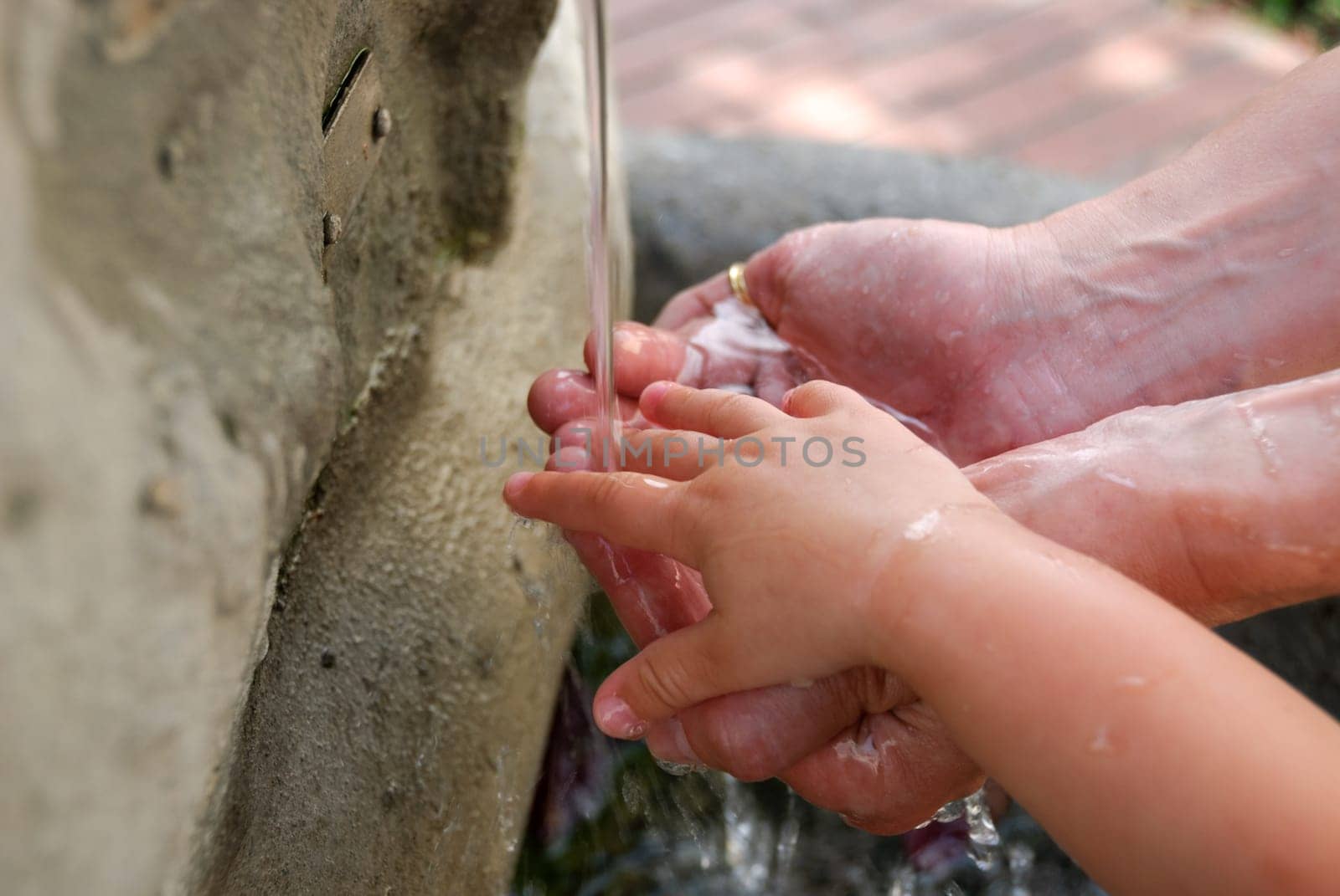 hands of mom and son under the fountain