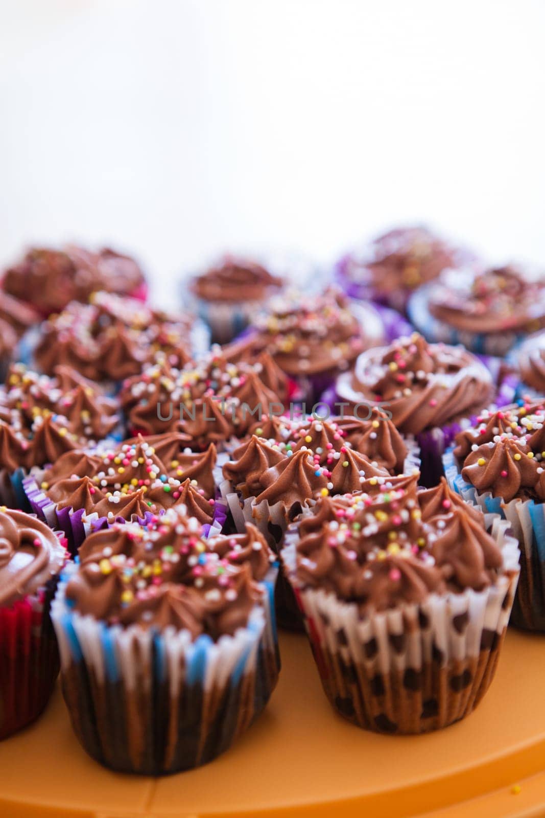 Closeup of chocolate cupcakes with decorative sprinkles on plastic tray
