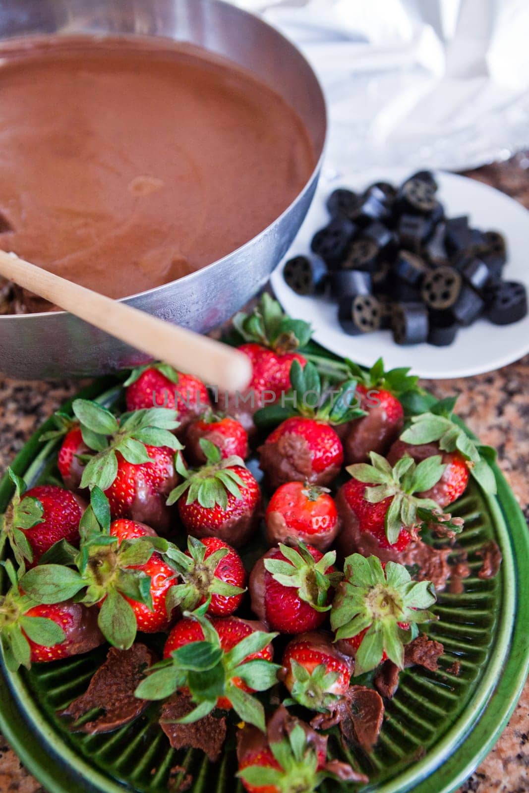 Plate of fresh strawberries and chocolate sauce in pan and licorice pieces