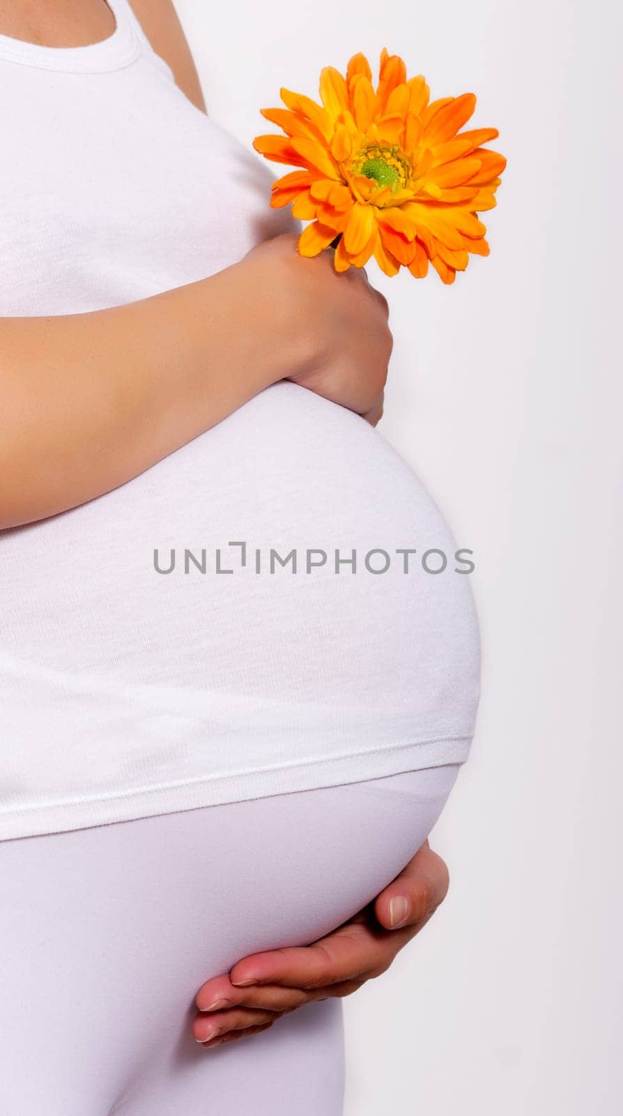 Pregnant woman touching here belly and holding a flower