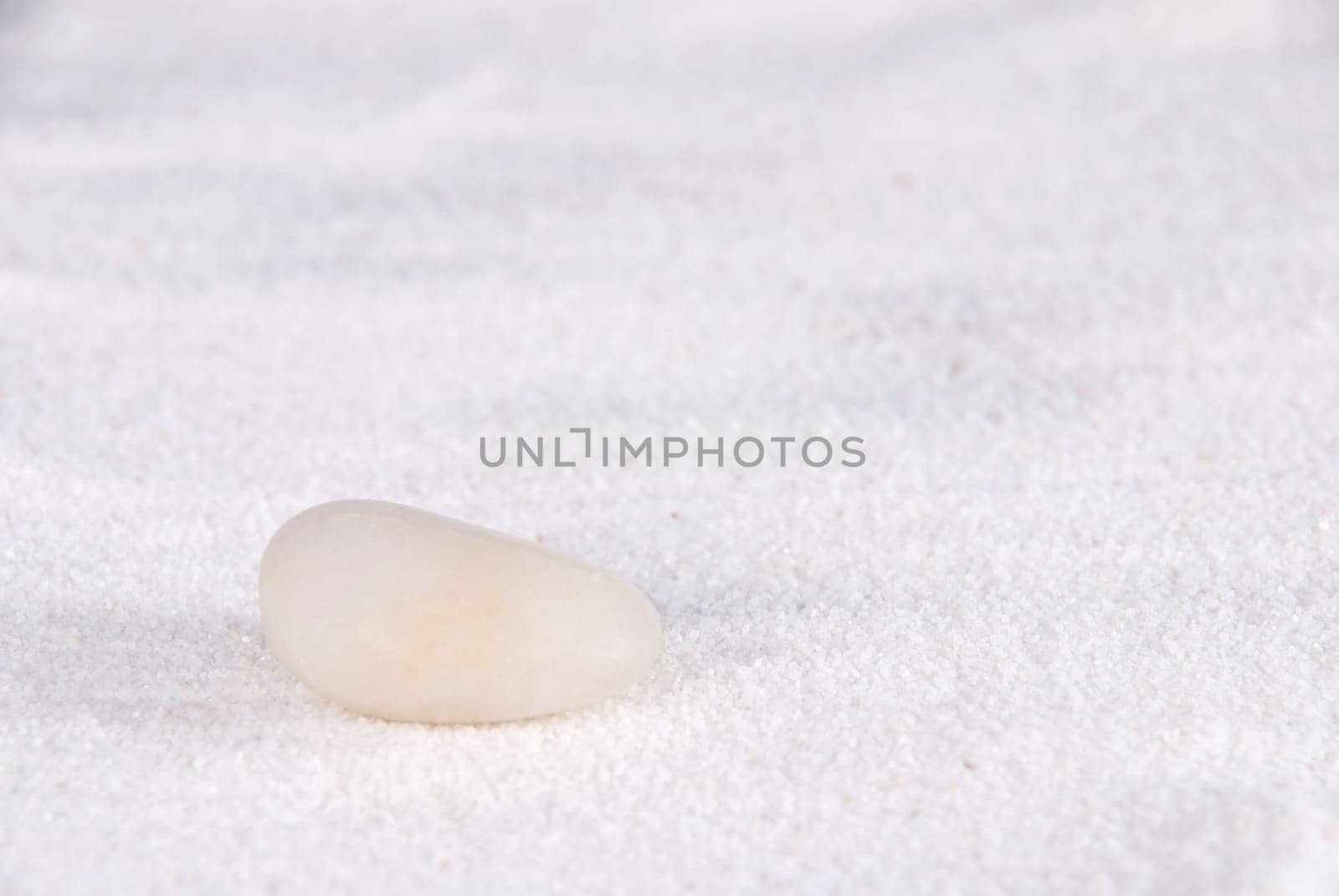 a white stone lying on white sand symbolizing calmness and power