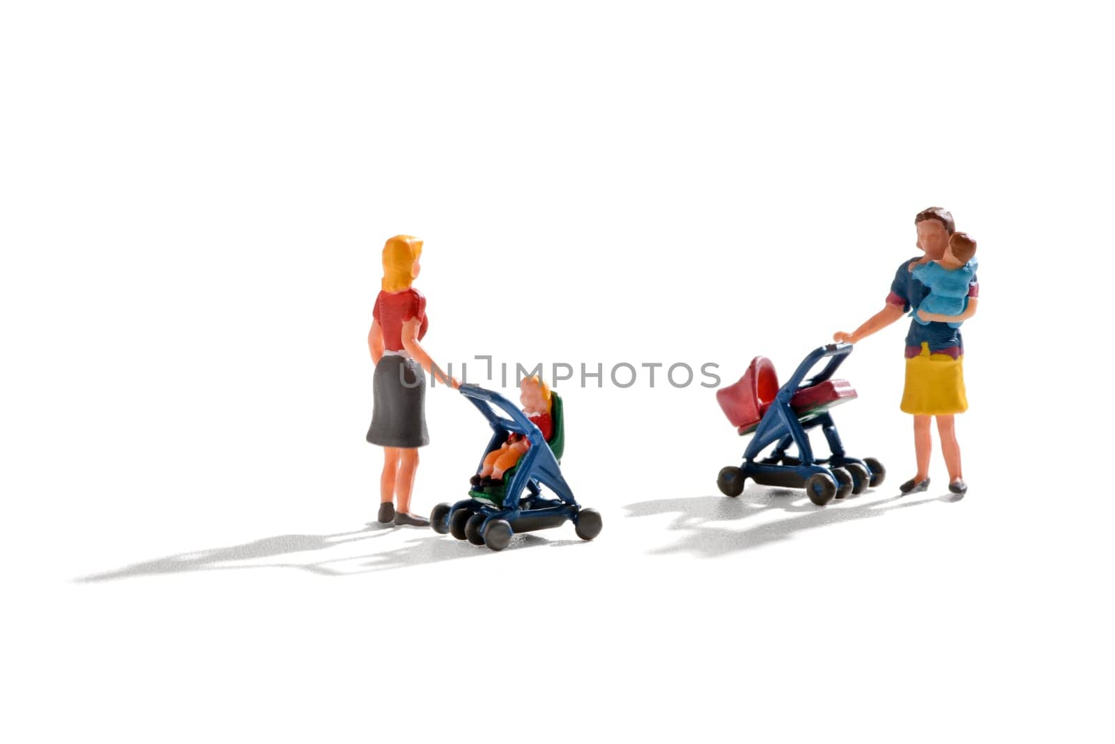 Two miniature figures of young mothers pushing their infants in a pram and pushchair with one holding her baby in her arms as they stand chatting on white
