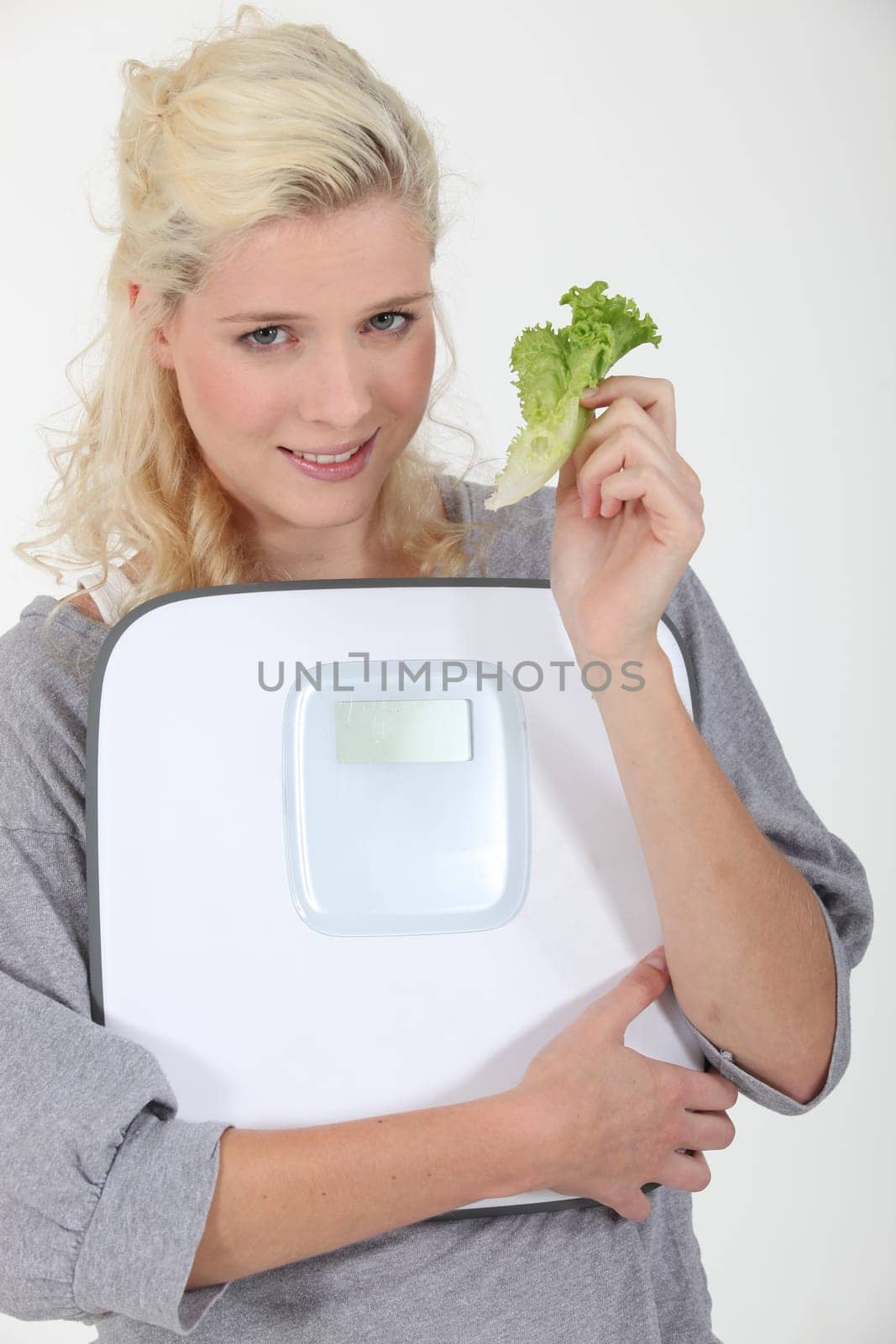 Woman holding lettuce leaf and scales