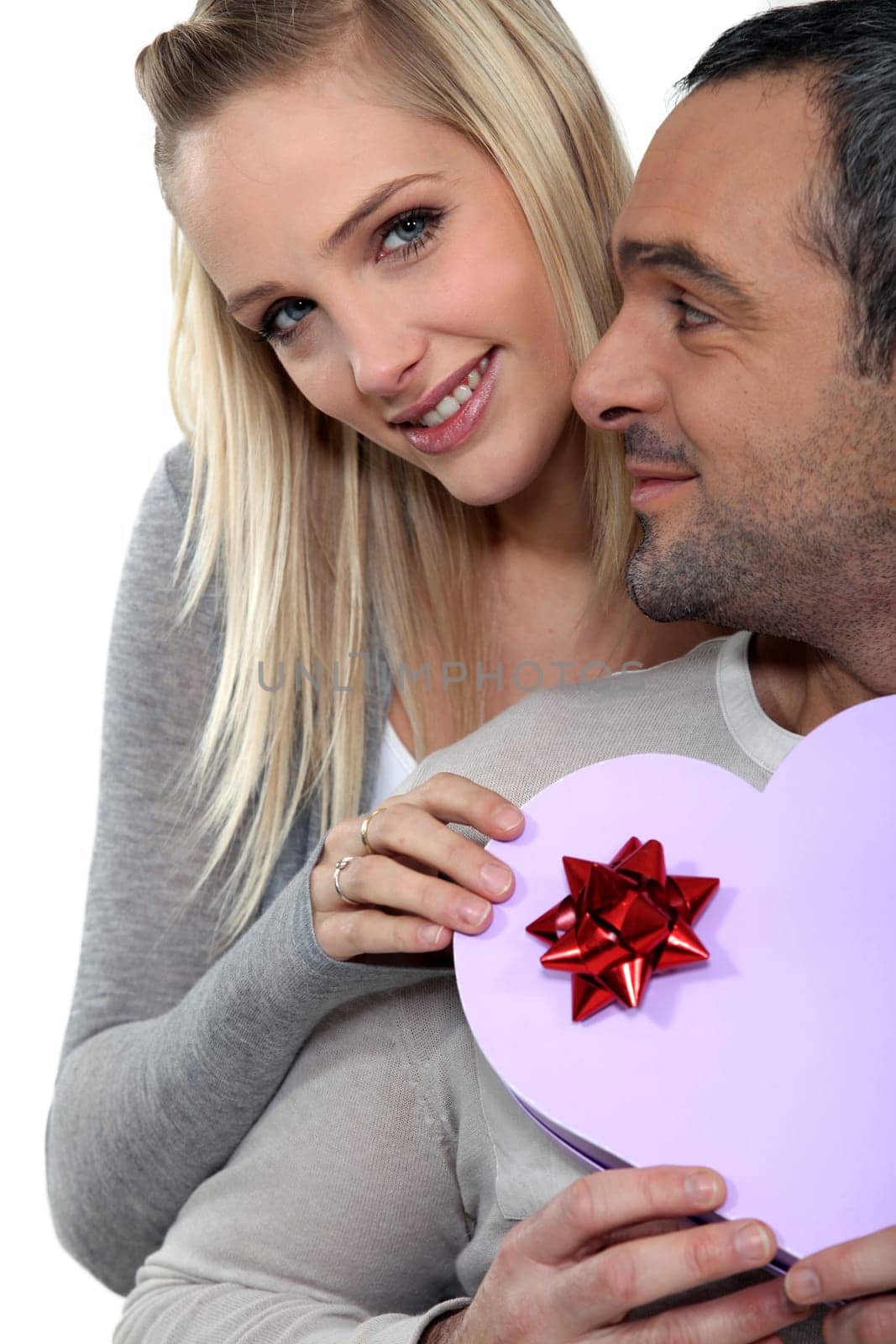 a woman giving a heart shaped box to her husband