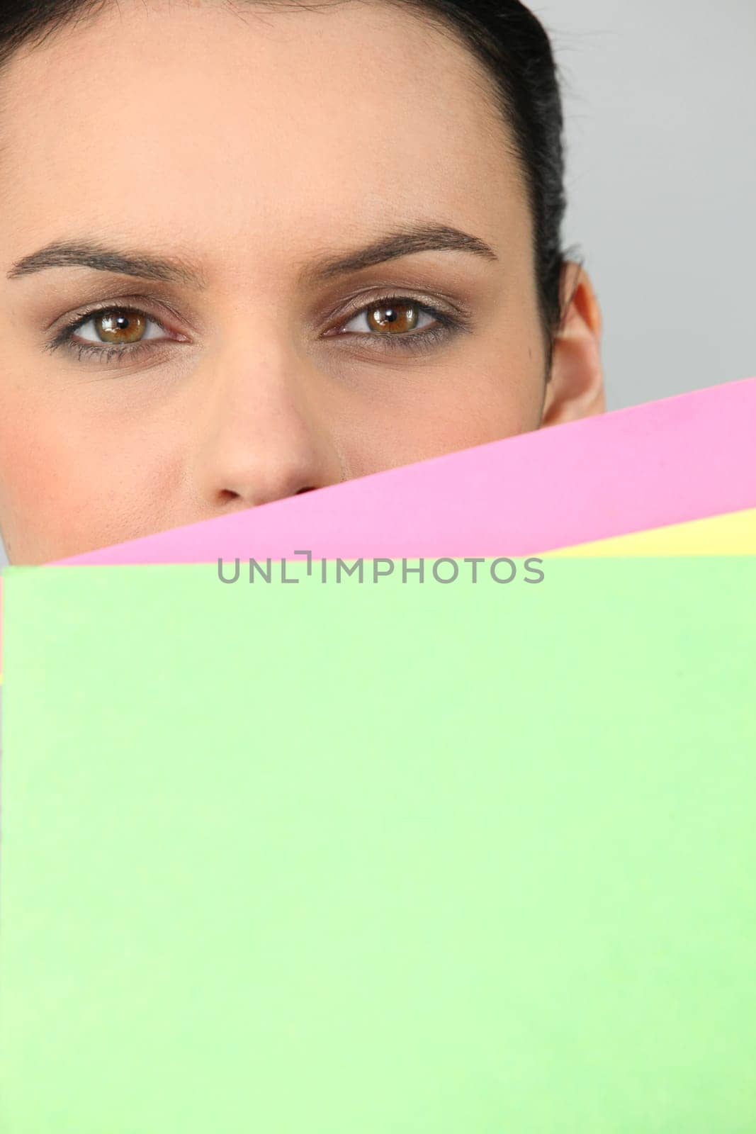 Woman hiding face behind documents