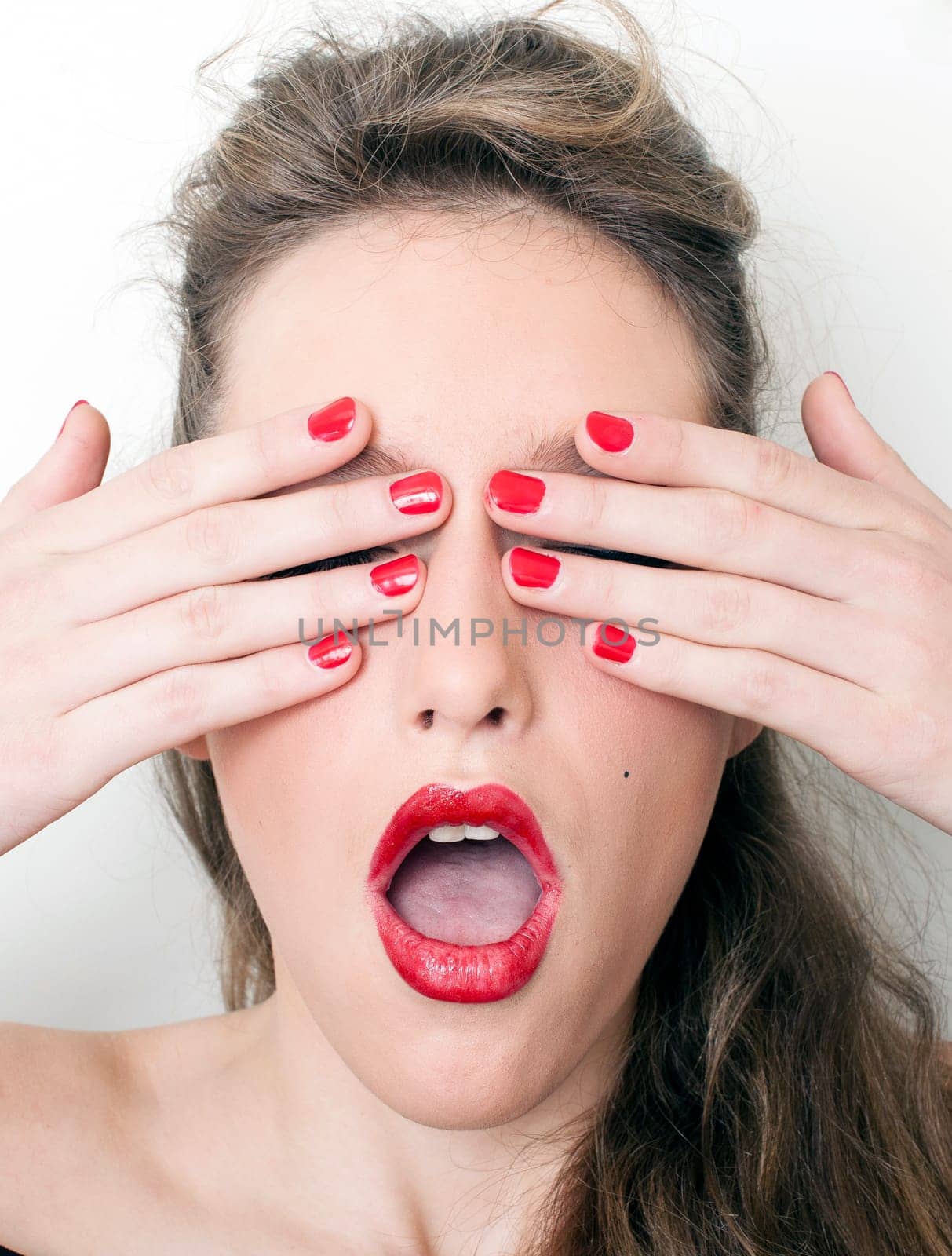 a charming young woman hiding her face behind her hands