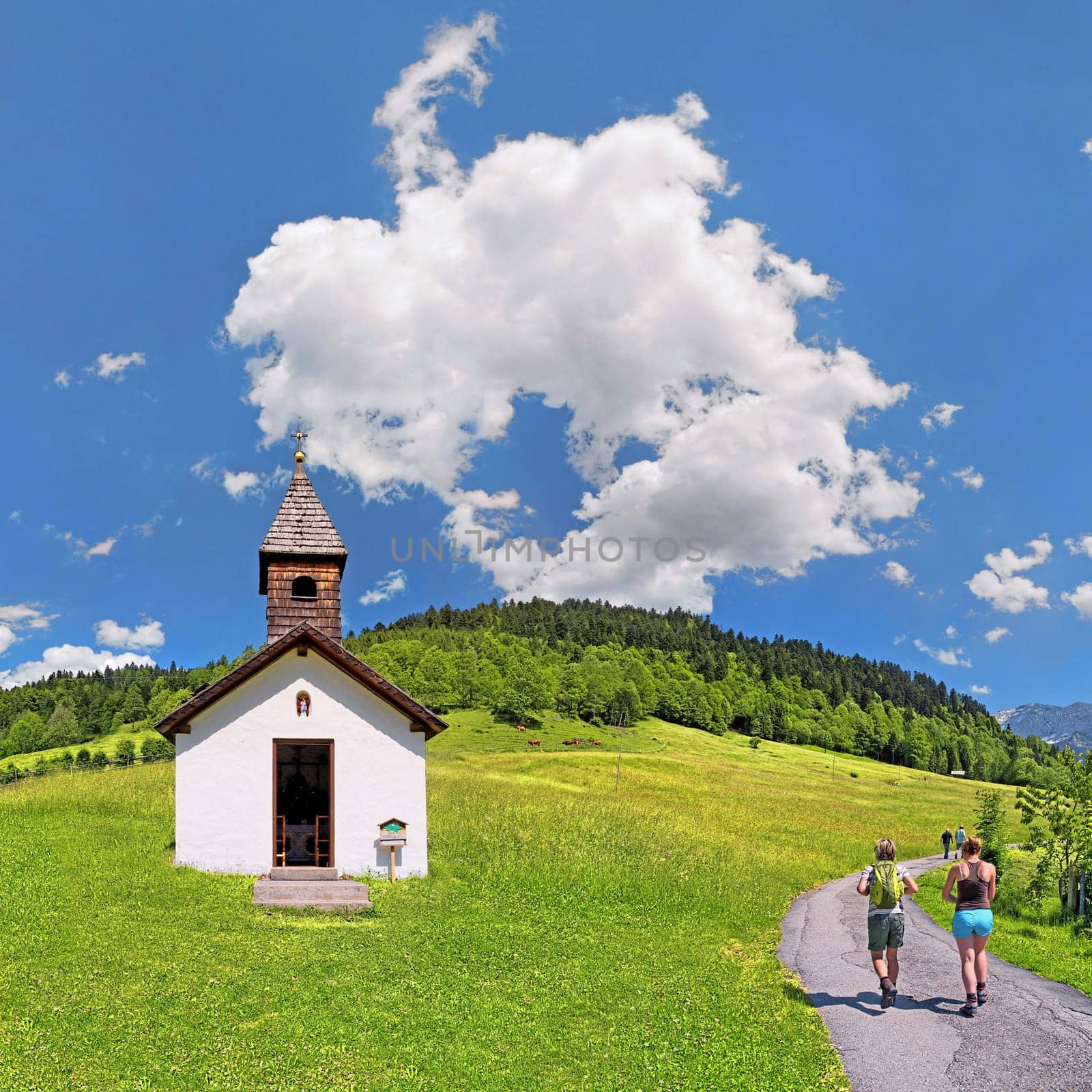 Small chapel at the Graseck with hikers and white-blue sky,Graseck,Garmisch-Partenkirchen,Bavaria,Germany,Europe