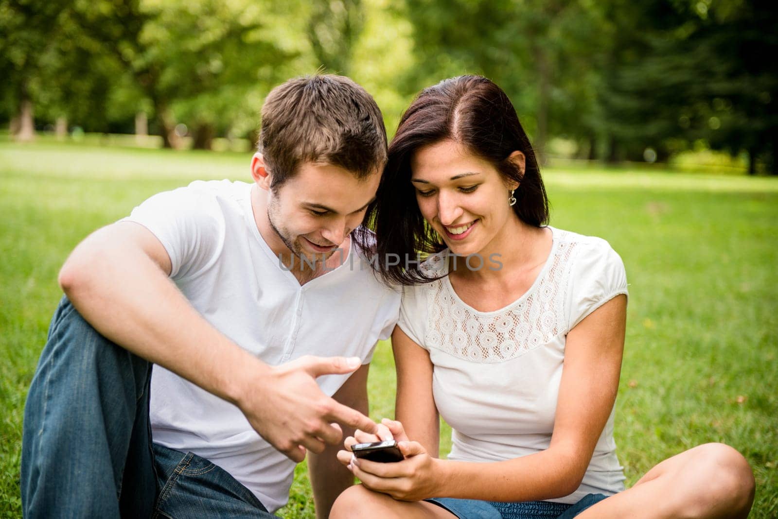 Young happy couple looking on mobile phone - outdooor in nature