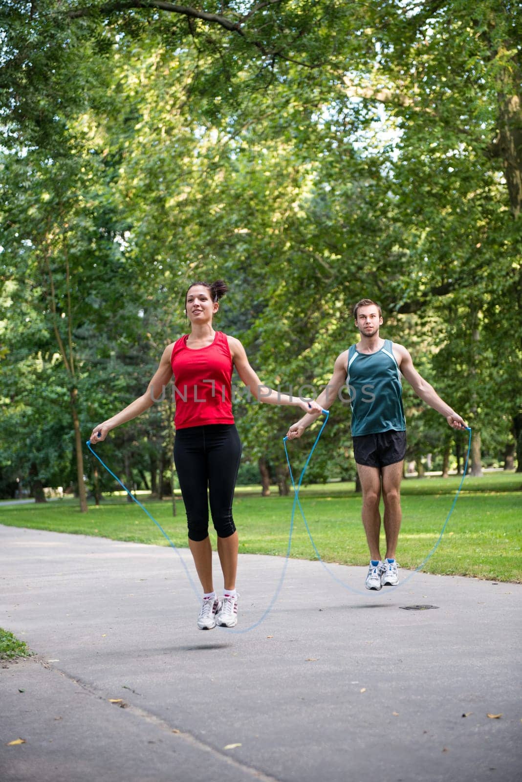 Young fitness couple exercising outdoor - jumping with skipping rope