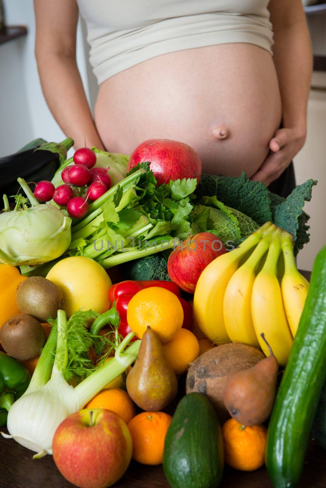 Detail of pregnant woman (belly) with abundance of vegetables and fruits