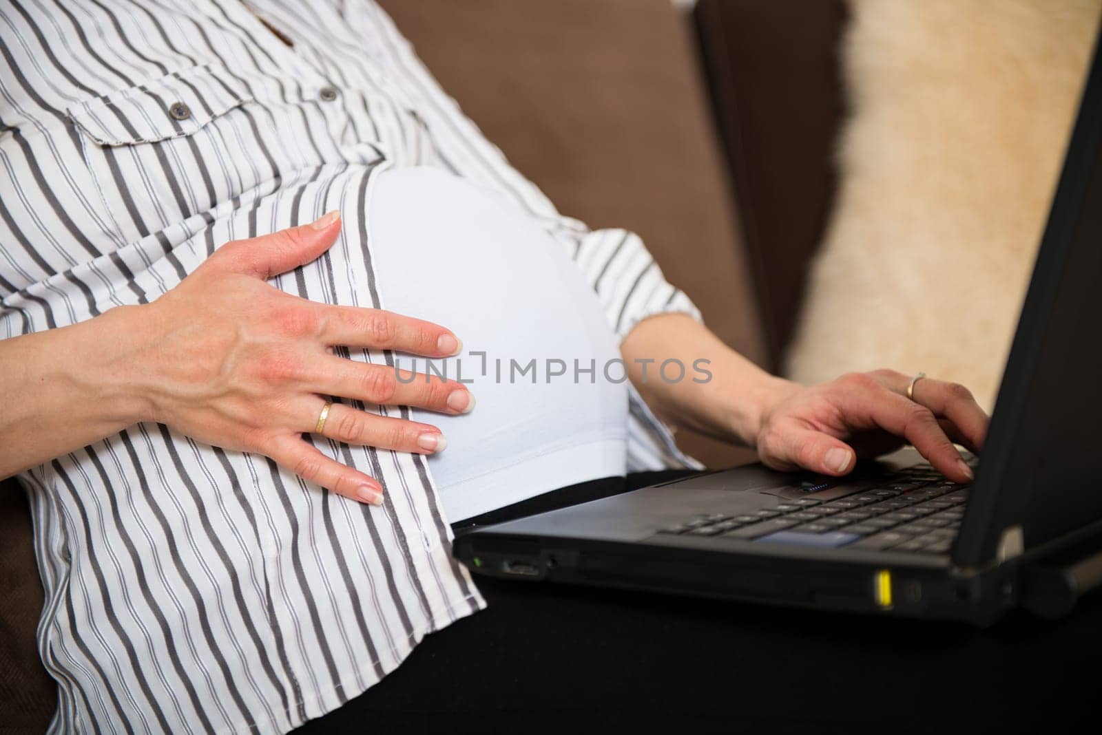 Torso of pregnant woman working on computer - home office