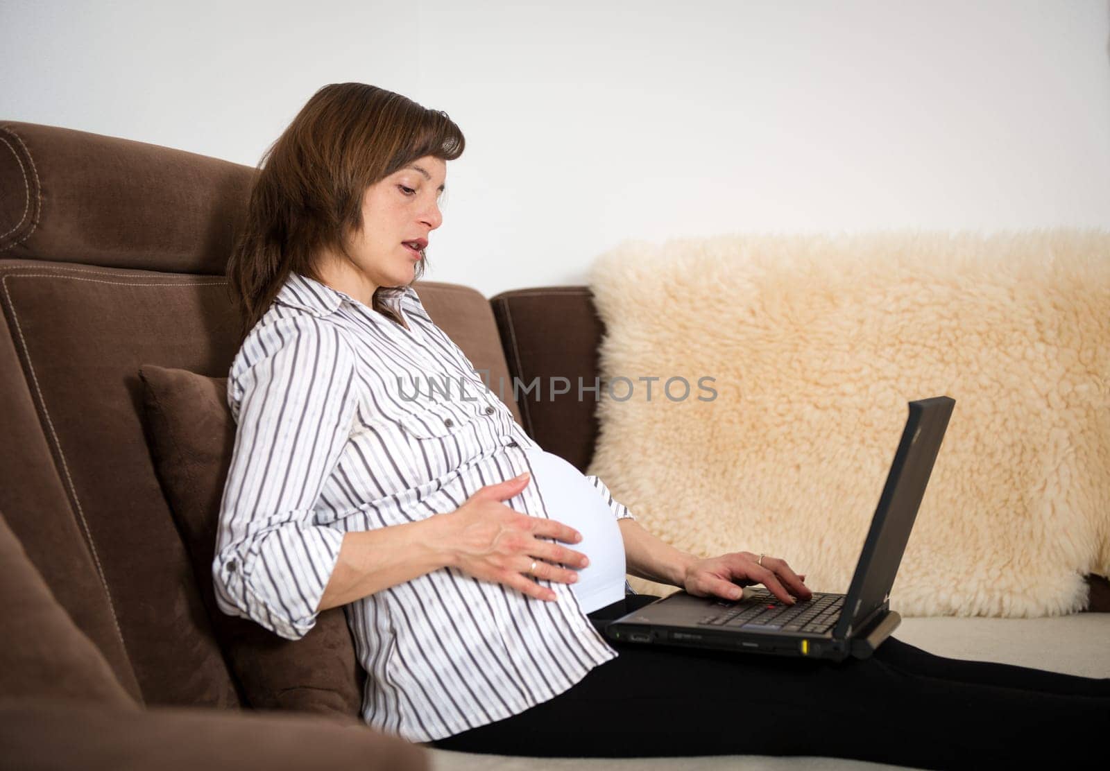 Pregnant woman working on laptop - home office